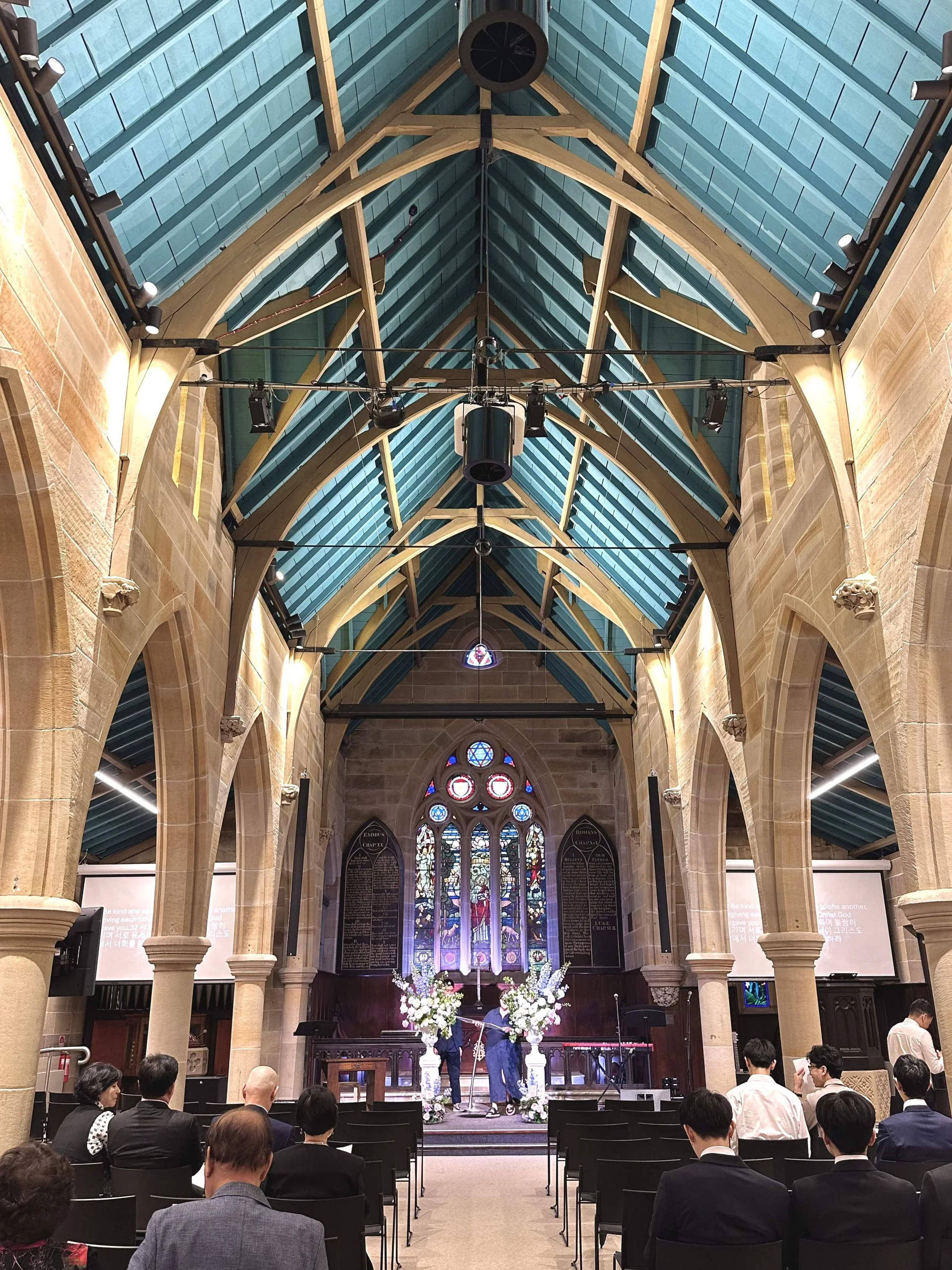 Wedding ceremony inside a historic Sydney church with vaulted ceilings and floral arrangements.