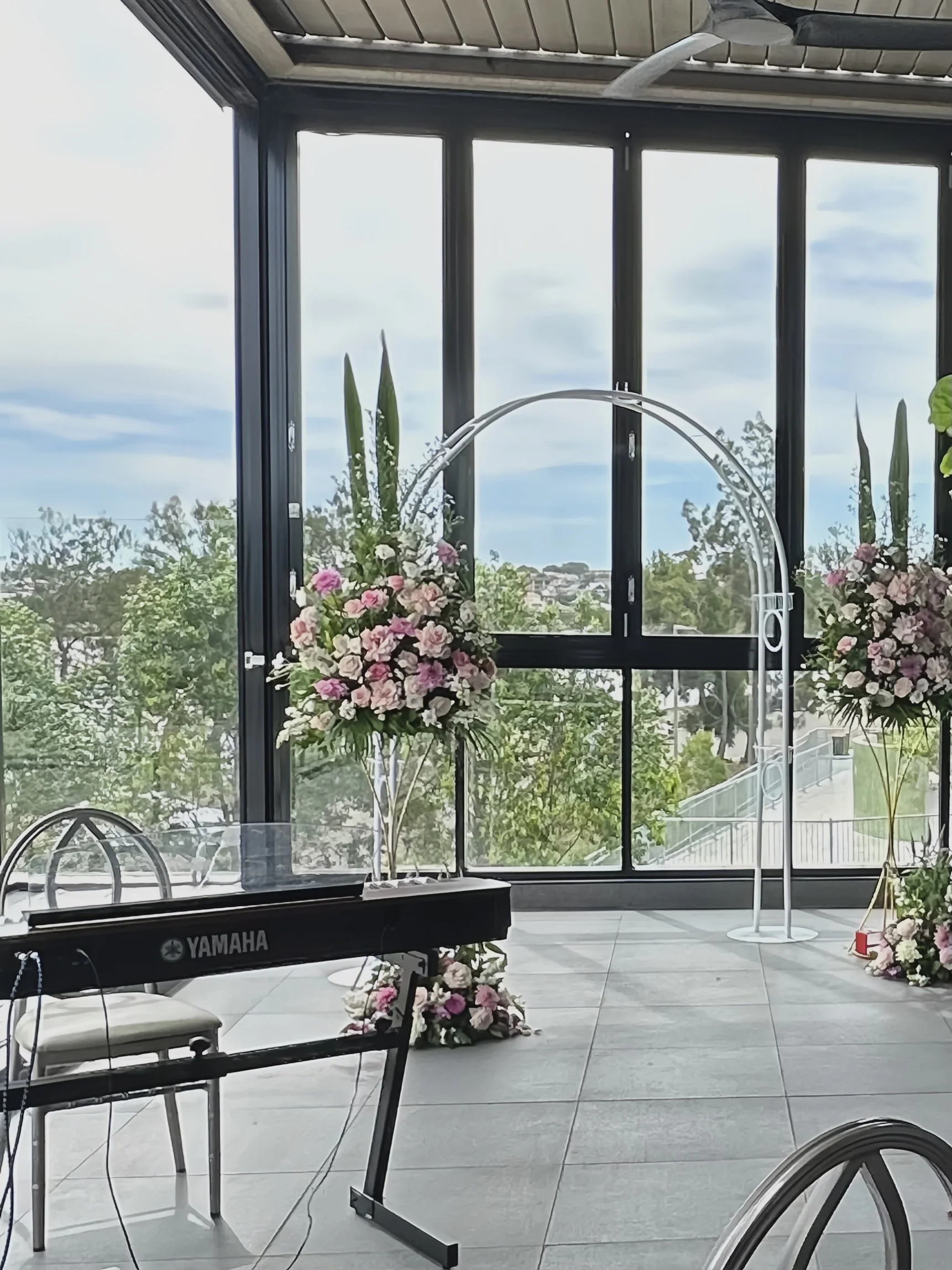 Light filled Sydney ceremony location featuring elevated floral arrangements and arch. 