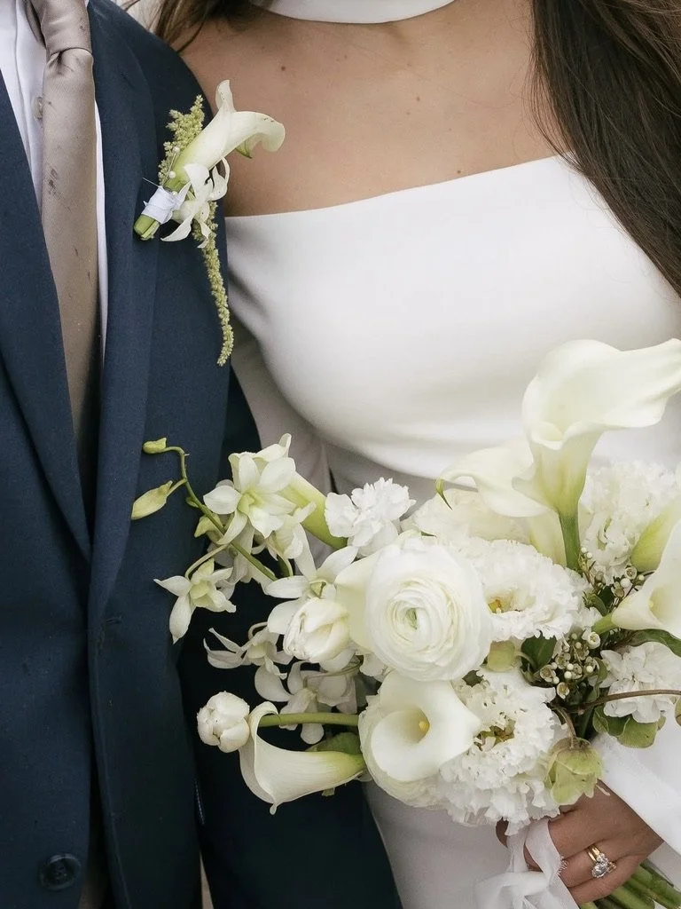 Modern all-white bridal bouquet featuring calla lilies, ranunculus, dendrobium orchids, and delicate seasonal blooms. Floral design by Butterfly’s Rest. Photography by Brianna Lee Photo.