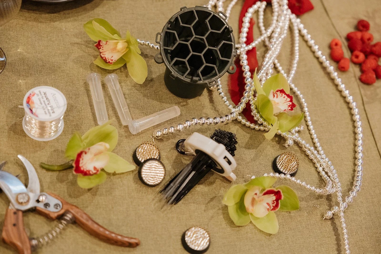 Behind-the-scenes floral design materials featuring orchids, sustainable floral mechanics, pearls, and arranging tools.