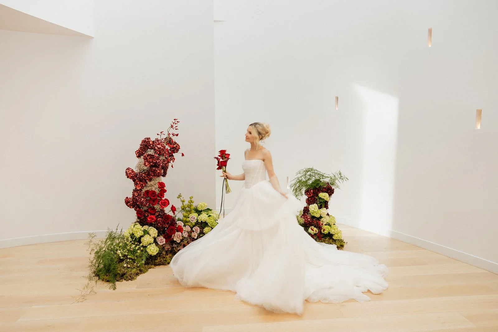 Modern bridal portrait featuring a rose bouquet and contemporary floral installation with red and green hydrangeas.