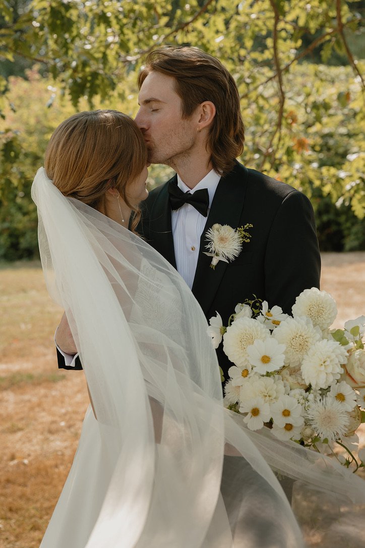 Bride and groom sharing a quiet moment at the Center for Urban Horticulture with an elegant white bridal bouquet and coordinating floral boutonnière featuring dahlias, cosmos, and textural seasonal blooms. Floral design by Butterfly’s Rest. Photograp