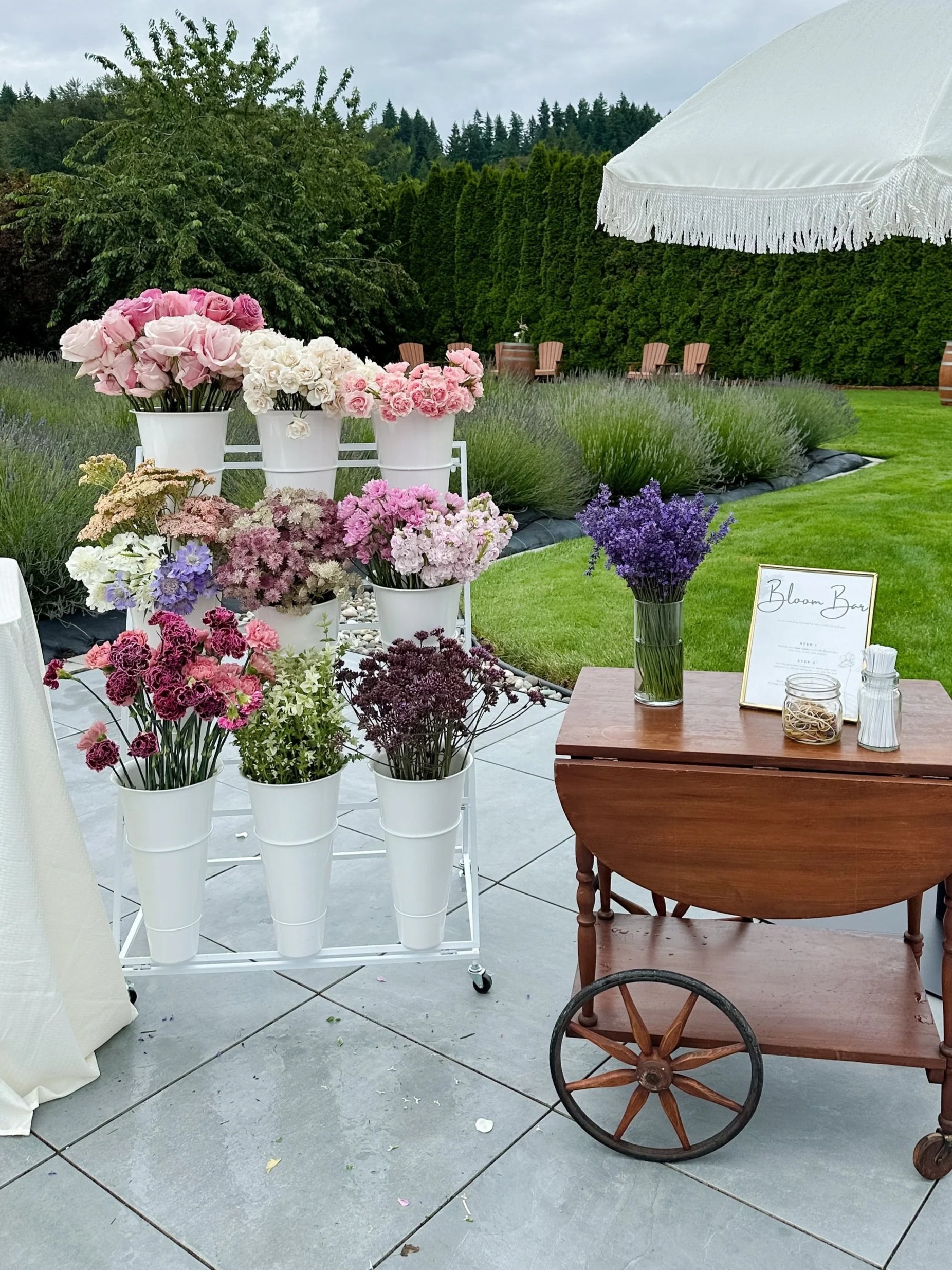 Outdoor Bloom Bar setup with fresh flowers and bouquet-making stations for guests at a private event.