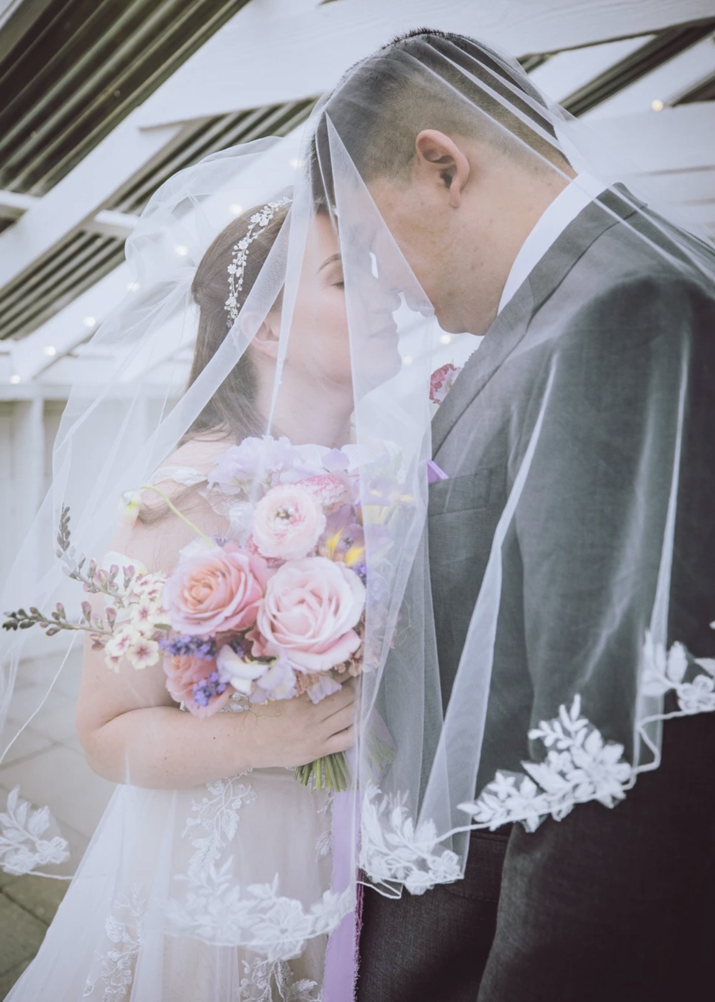 Bride and groom sharing an intimate moment, featuring a pastel bridal bouquet with seasonal flowers.