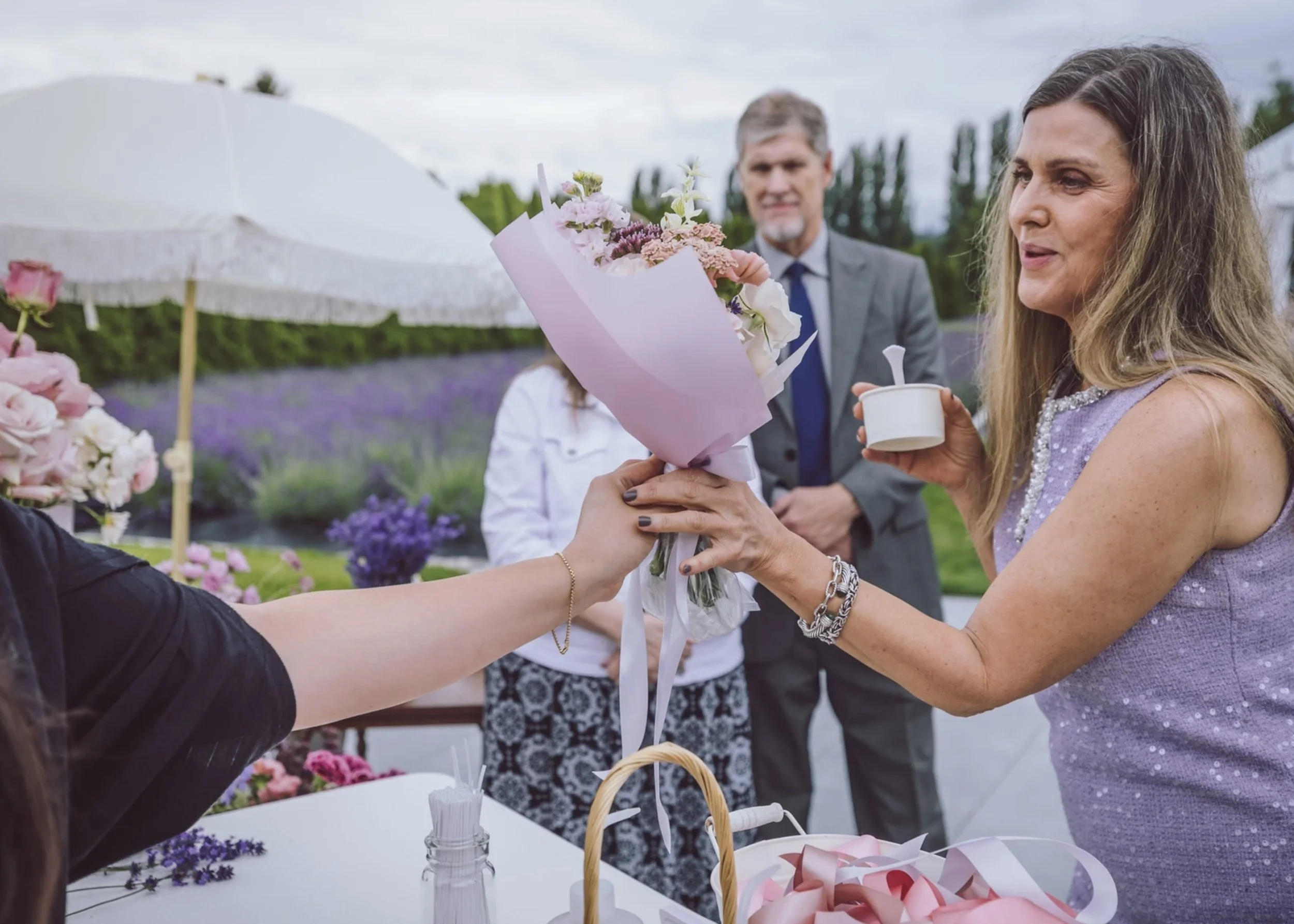 Guest receiving a hand-tied bouquet from a Bloom Bar floral experience at an outdoor celebration.