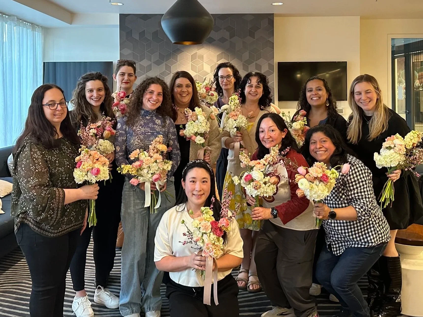 A group of women holding bouquets of flowers after a private floral design workshop.