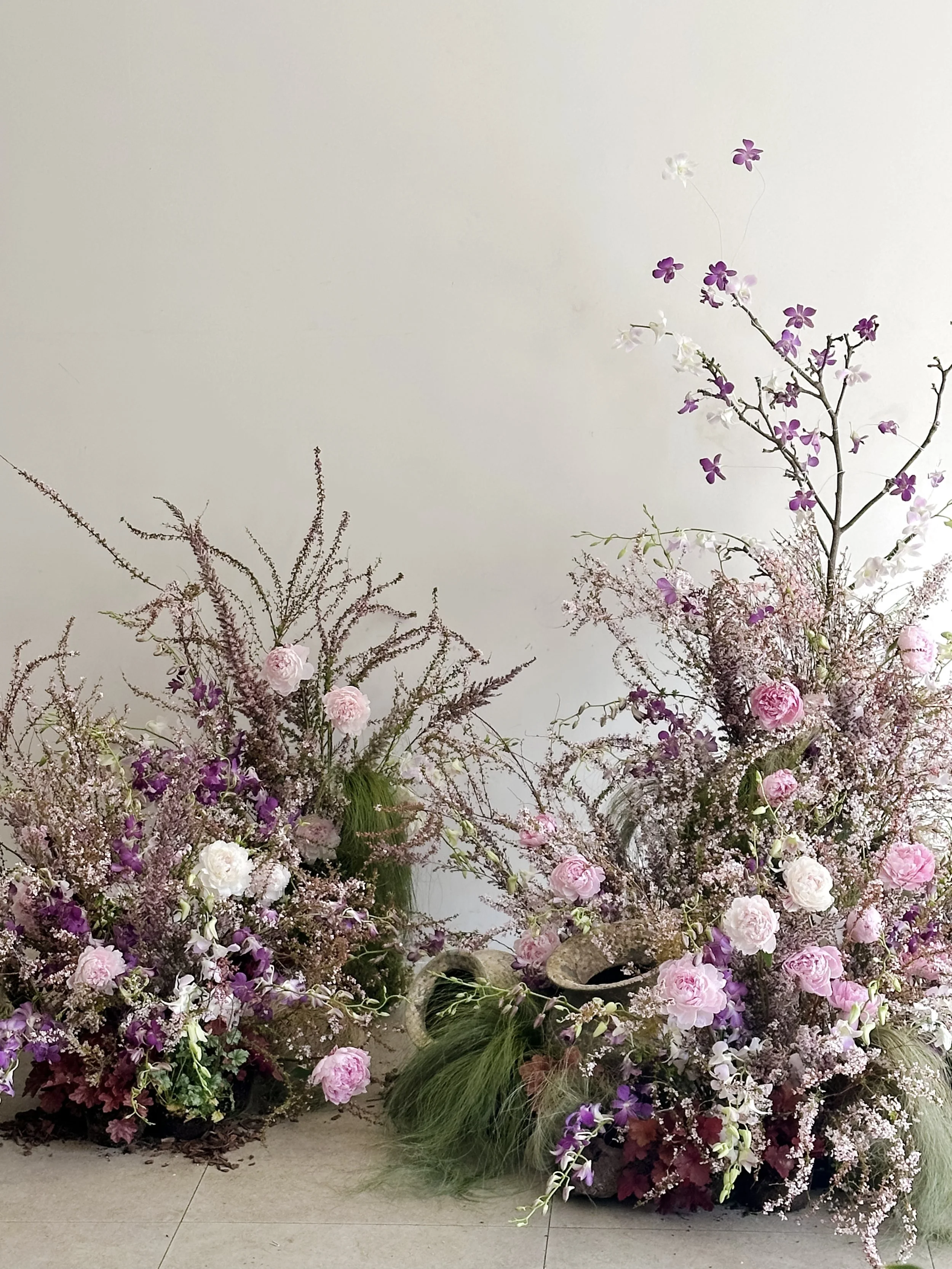 Garden-inspired floral installation featuring peonies, flowering branches, and spring blooms in shades of pink and lavender.