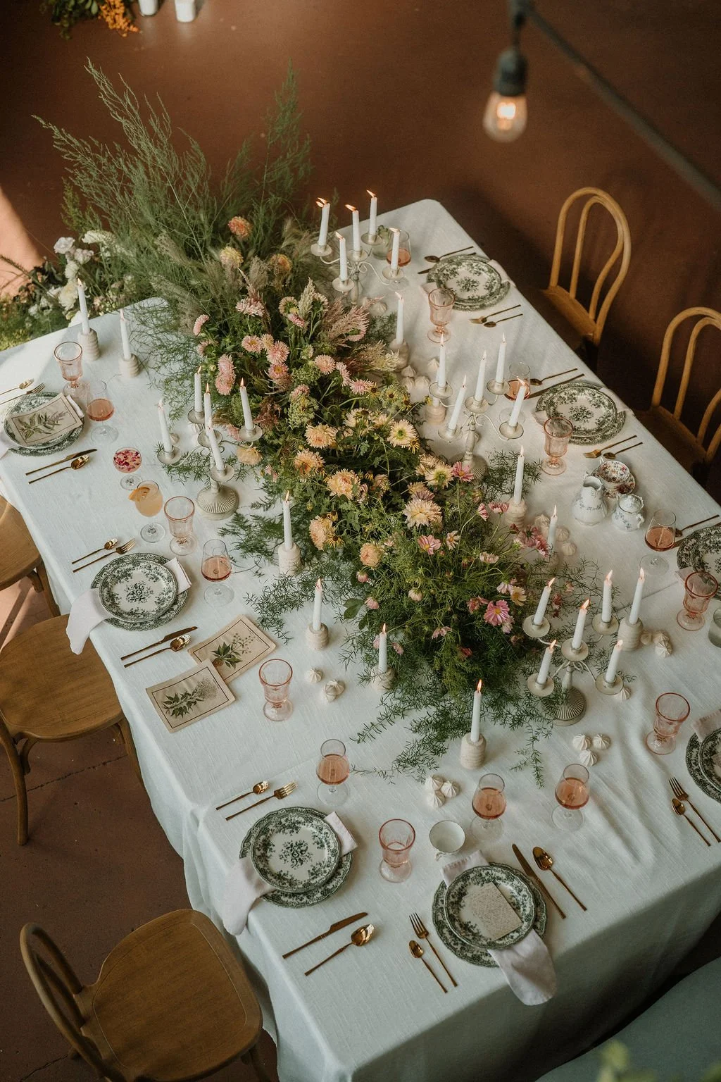 Garden-inspired reception tablescape featuring meadow-style florals, candlelight, and an abundant floral runner.
