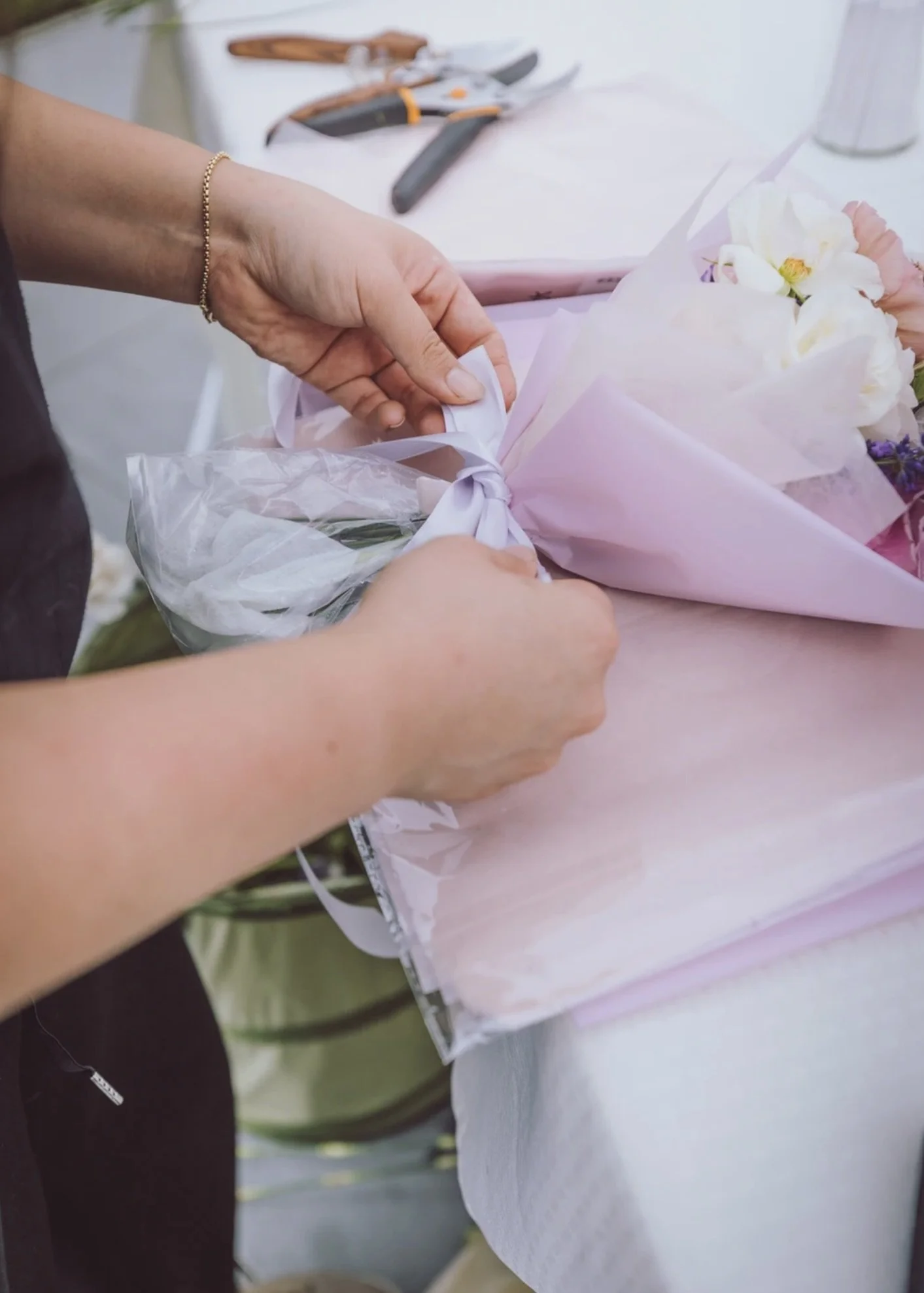 Freshly arranged bouquet being wrapped with ribbon at an interactive Bloom Bar event.