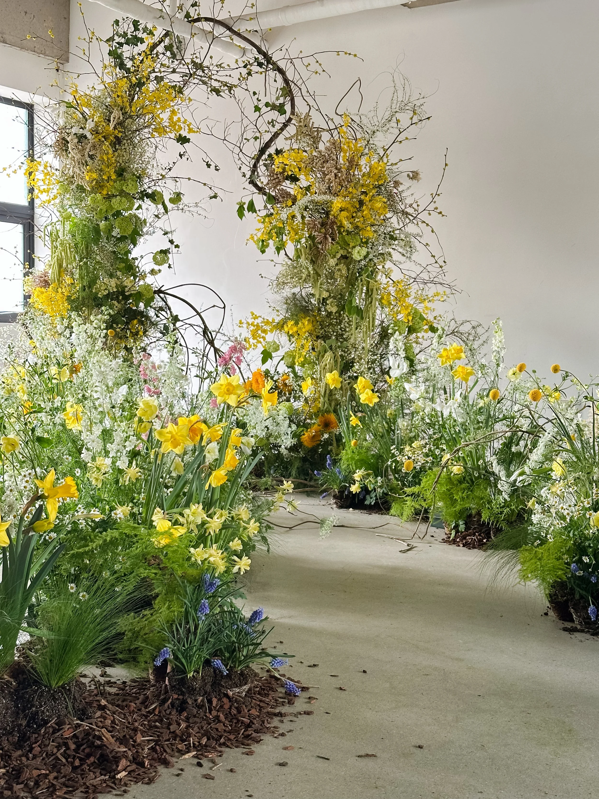 Meadow-inspired floral installation featuring spring blooms, flowering branches, and an immersive garden aisle.
