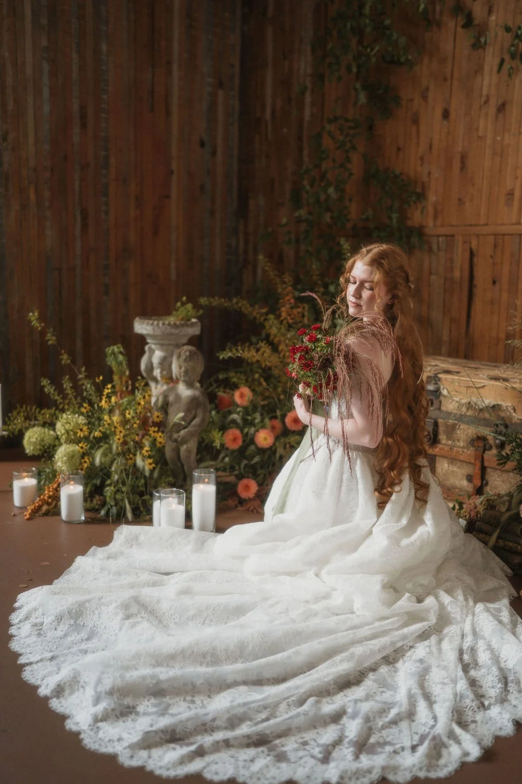 Bride holding a wildflower-inspired bridal bouquet surrounded by lush floral arrangements and candlelight.