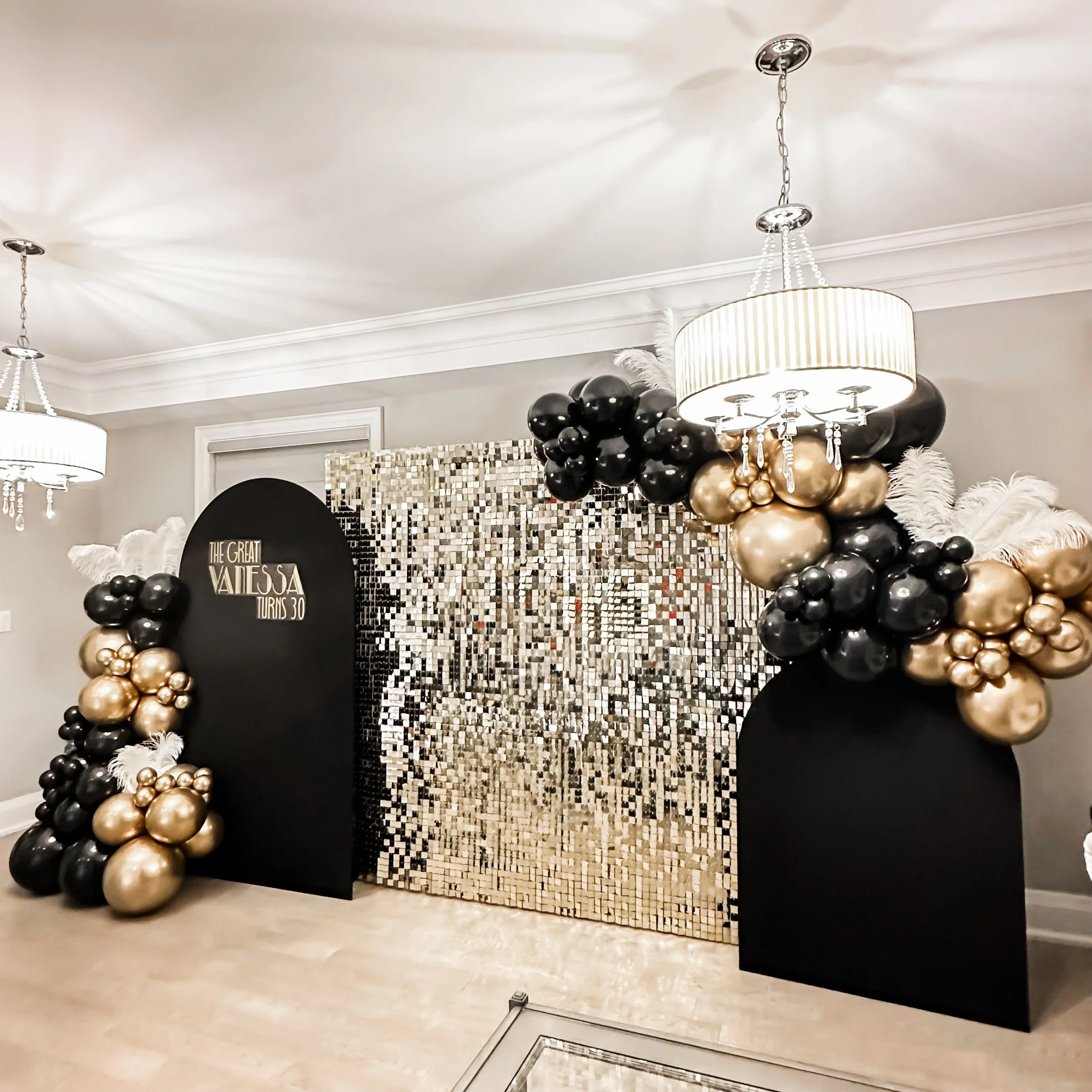 Decorative photo backdrop with black and gold balloons, white feathers, and a digital mosaic backdrop, celebrating Valerie's 30th birthday.