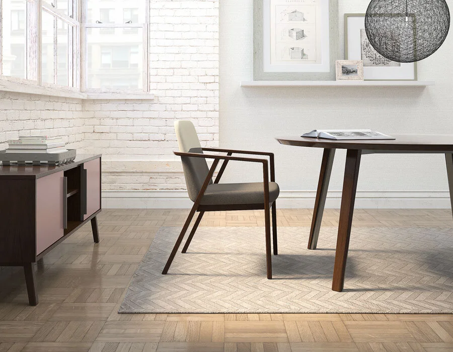 A modern, minimalist home office with a desk, a chair, a sideboard, and framed art on the wall, illuminated by natural light from large windows.