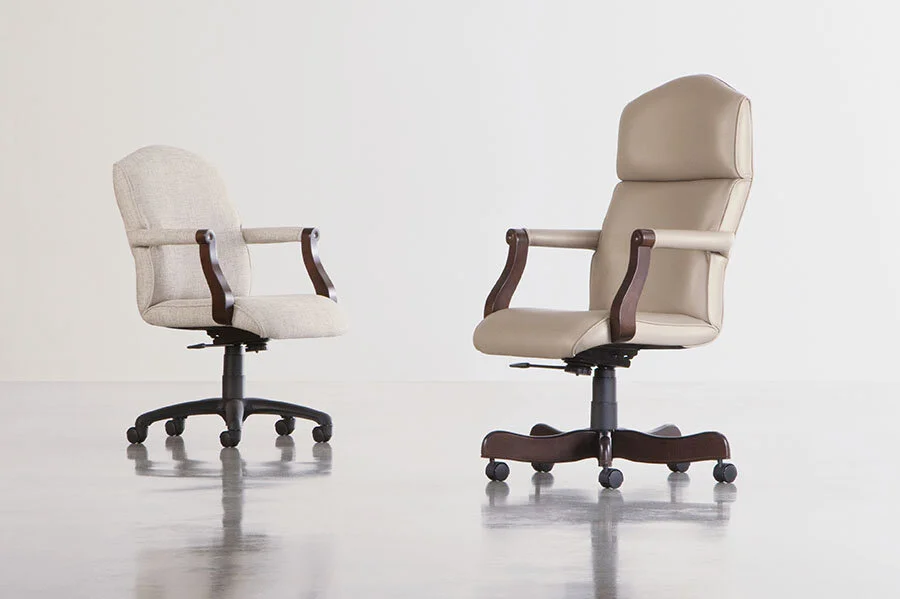 Two office chairs, one smaller and one larger, in a minimalistic room with a plain white background.