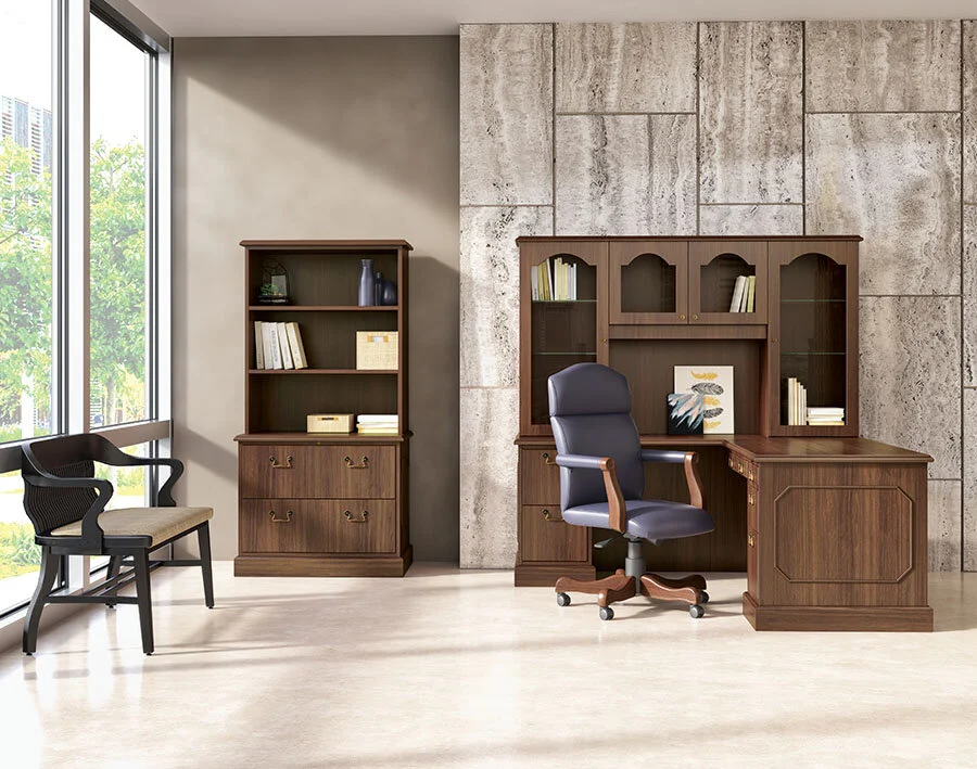 Office space with large window, wooden desk, black leather office chair, and bookshelf with decorative items and books.