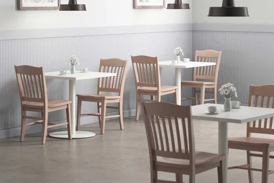 Empty dining area with white tables, light wood chairs, and minimal decor in a bright, modern setting.