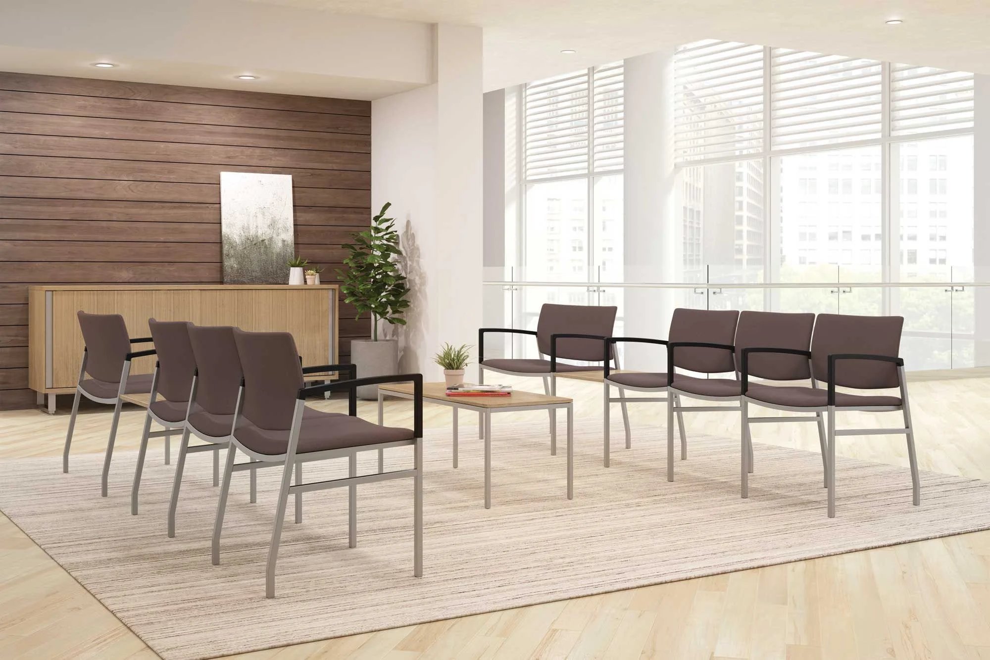 Empty waiting room with six chairs, a small table with a plant and books, a sideboard with decorative items, and large windows with city views.