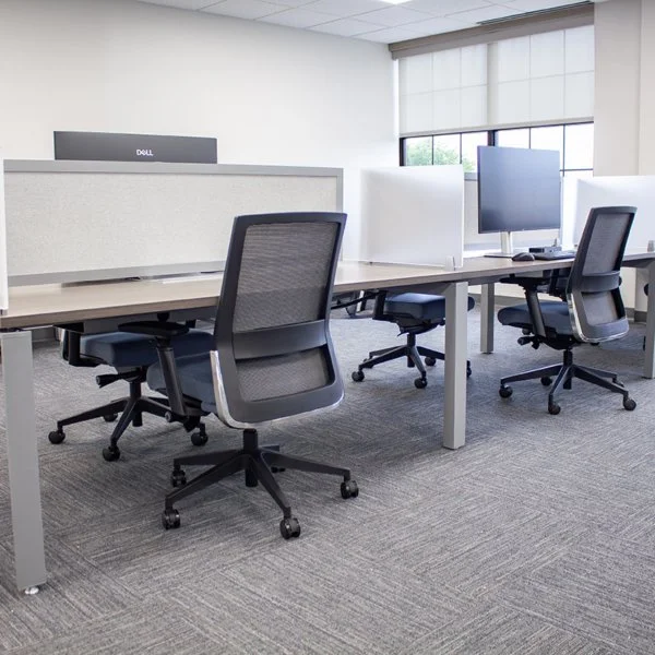 Empty modern office with workstations, desktop computers, and office chairs.