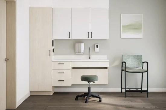 Medical examination room with white cabinets, a sink, a gray chair, and a gray stool, in a minimal setting