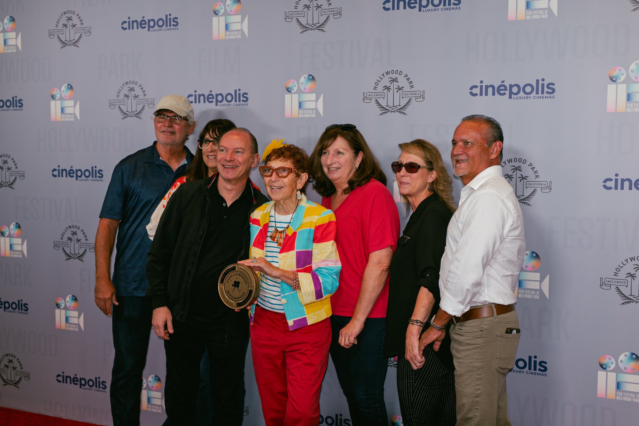 Group of seven people standing together on a red carpet at the Hollywood Park film festival, posing in front of a step and repeat banner with logos for Cinépolis and Hollywood Park.