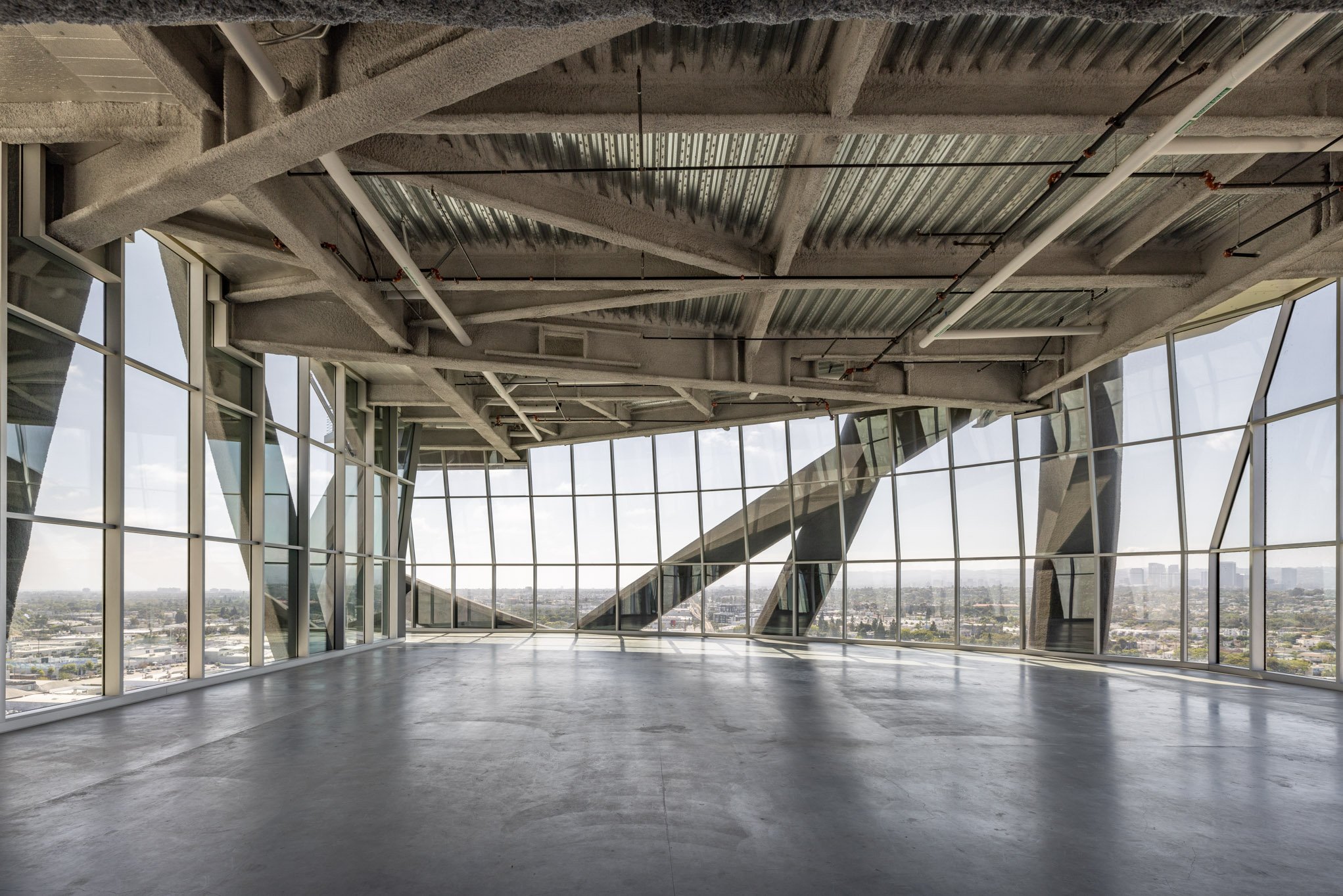 Empty modern interior space with large glass windows and steel structure.