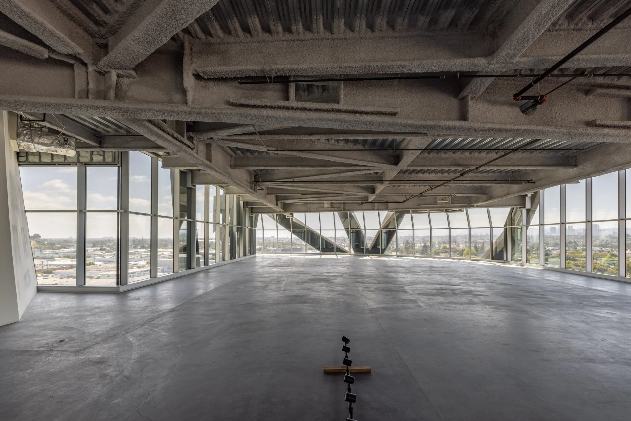 Empty, unfinished interior space with large glass windows and an expansive city view.
