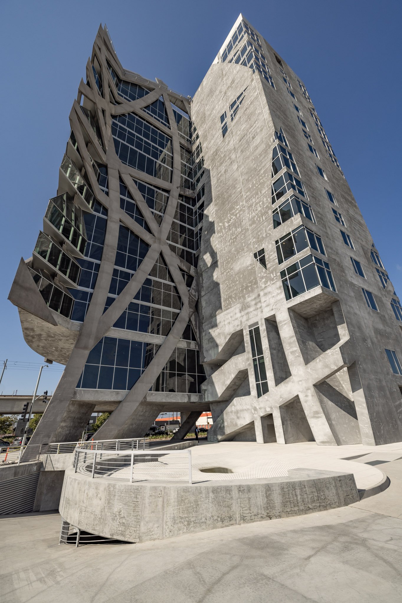Modern high-rise building with an architectural design featuring angular concrete supports and large glass windows.