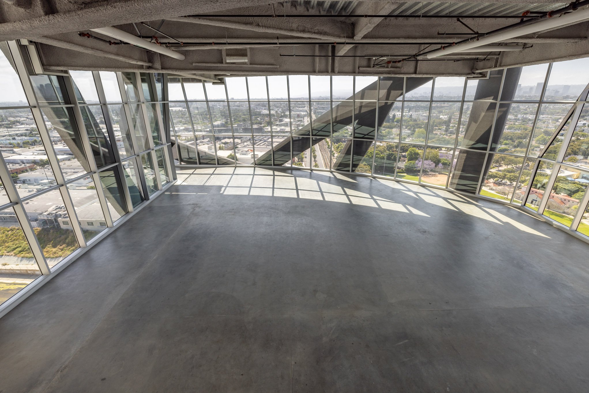 Empty room with large floor-to-ceiling windows and a view of the cityscape.