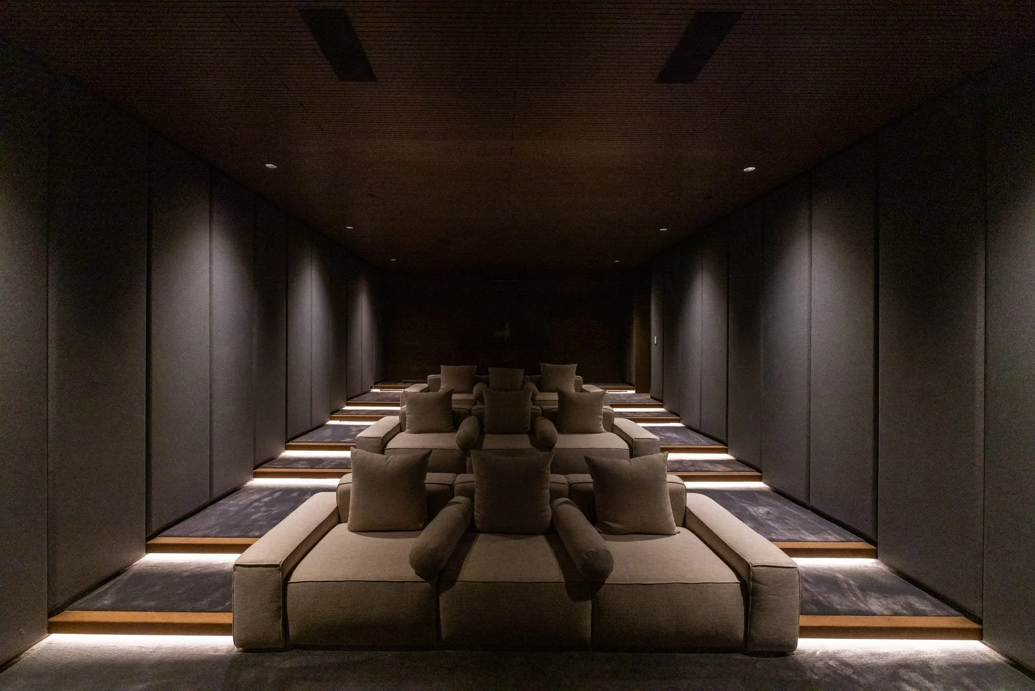 Luxurious, darkly lit lounge with plush chairs and sofas, minimalistic design, and subdued lighting.