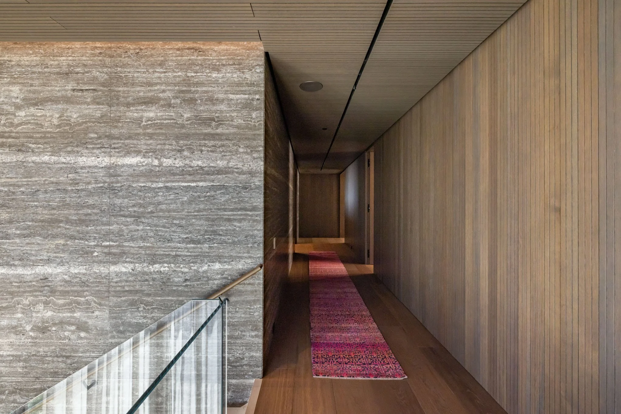 A hallway with wooden panel walls and a patterned red carpet runner.