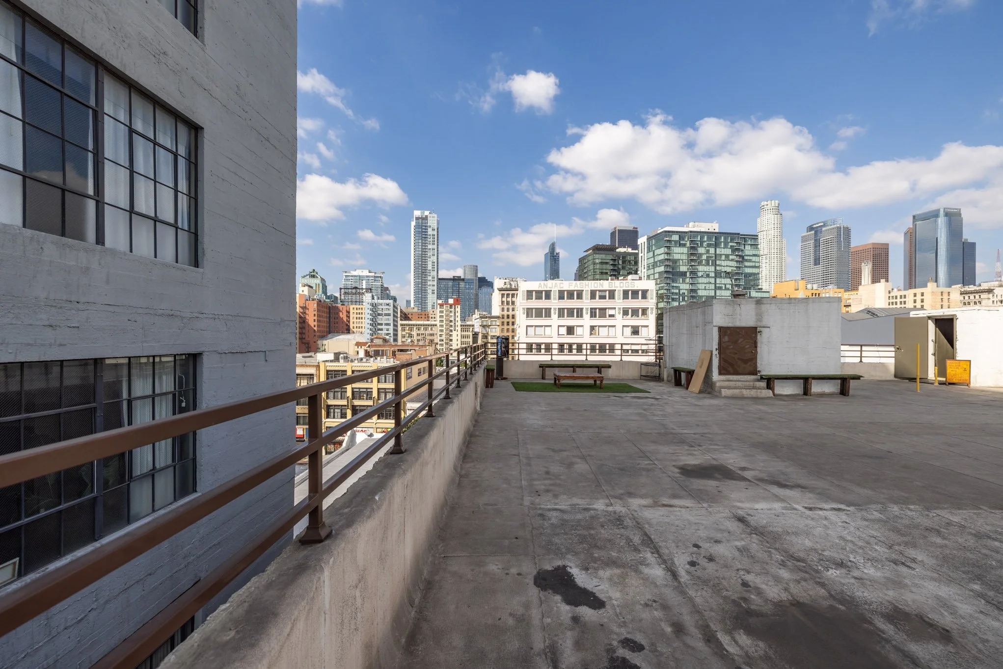 City skyline view from a rooftop with benches and a cloudy sky.
