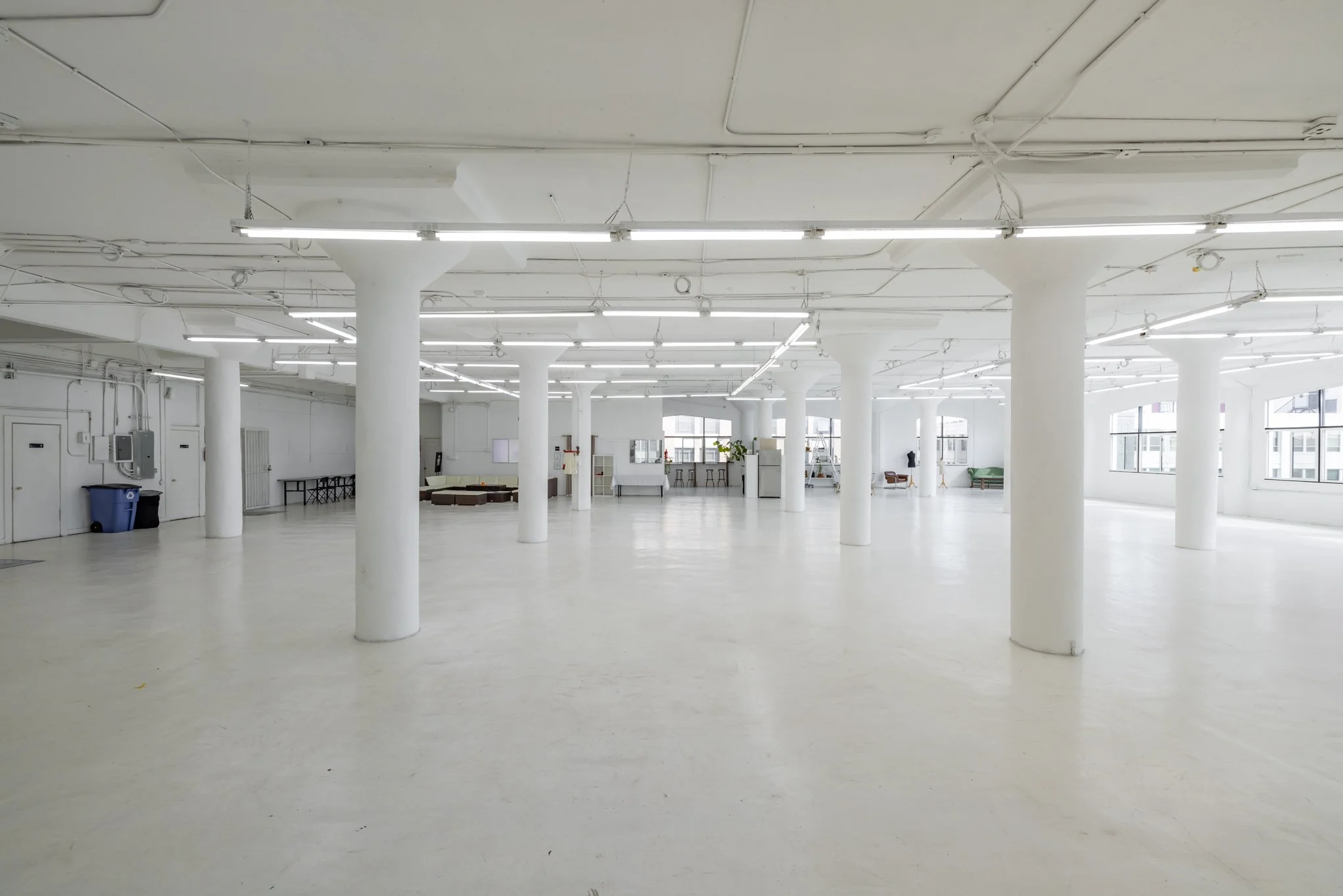 Empty, white, spacious industrial or commercial space with white columns and large windows.
