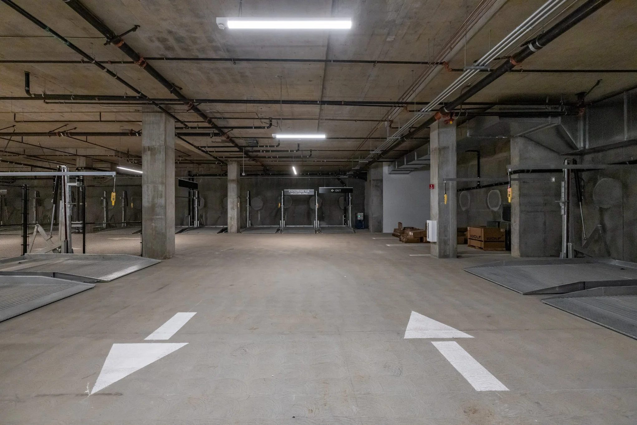 Empty indoor parking garage with white arrows painted on the floor pointing forward.