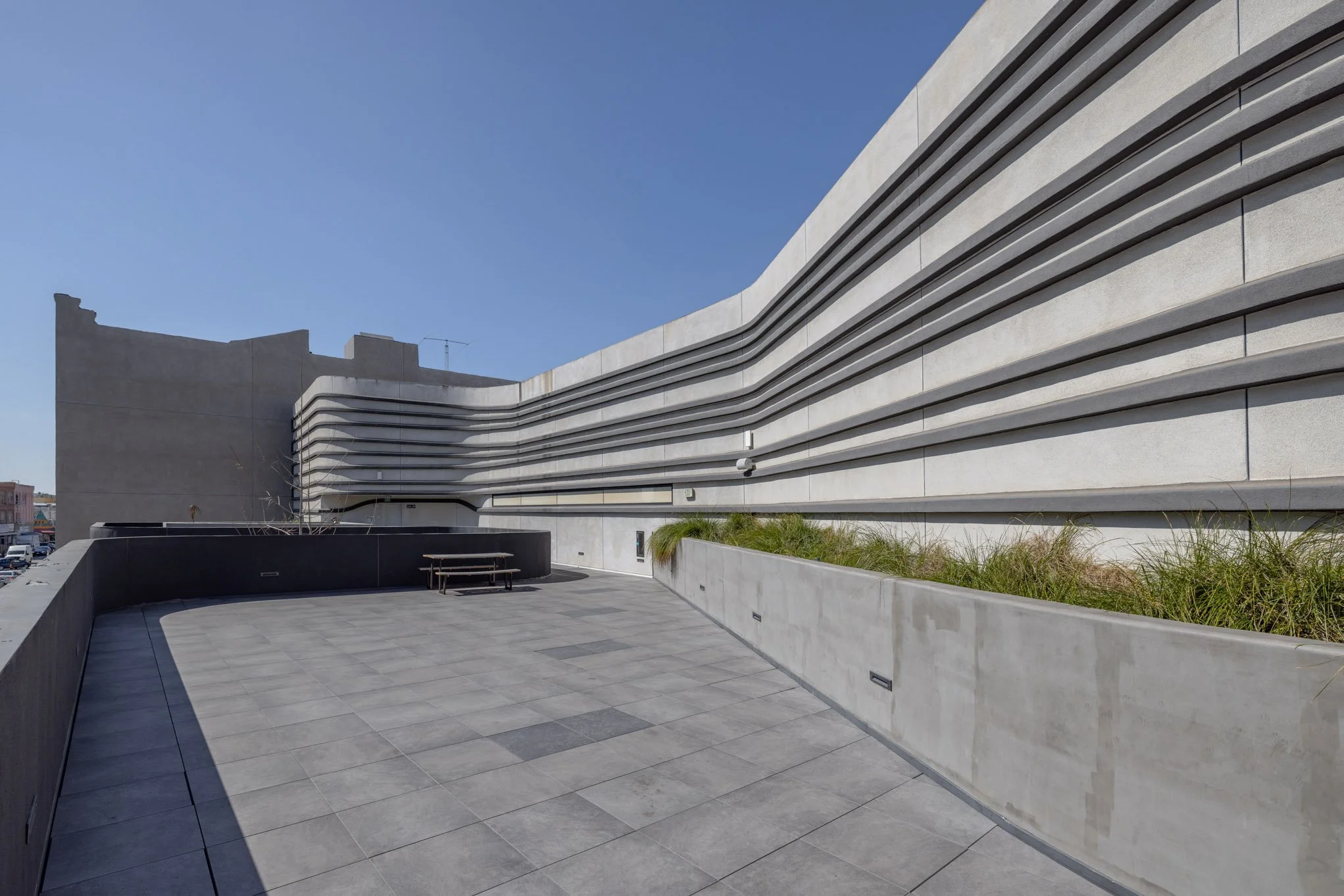 Modern building with horizontal lines and a spacious outdoor terrace with seating and planters