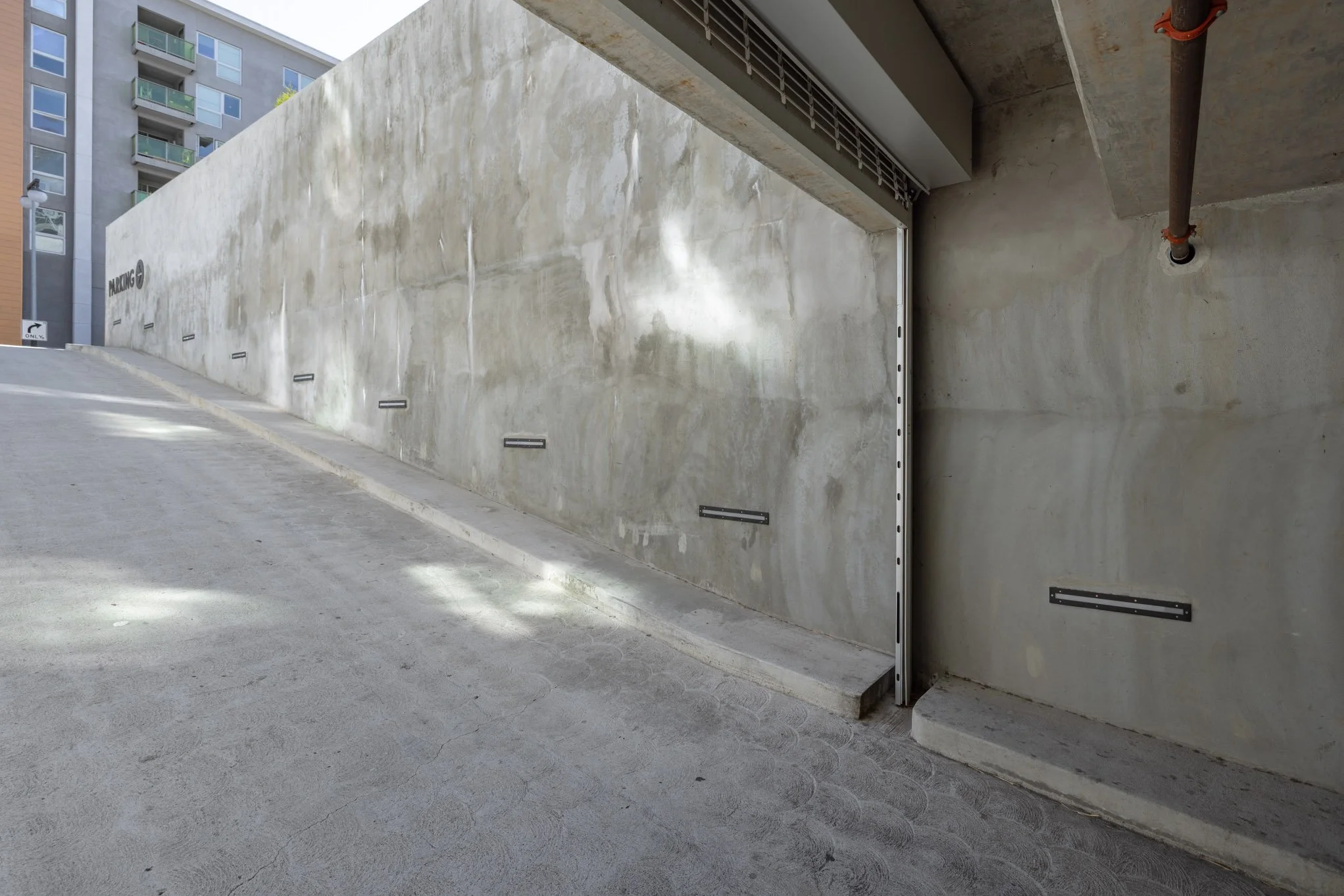 Underground parking garage entrance with concrete walls and a partially open garage door.