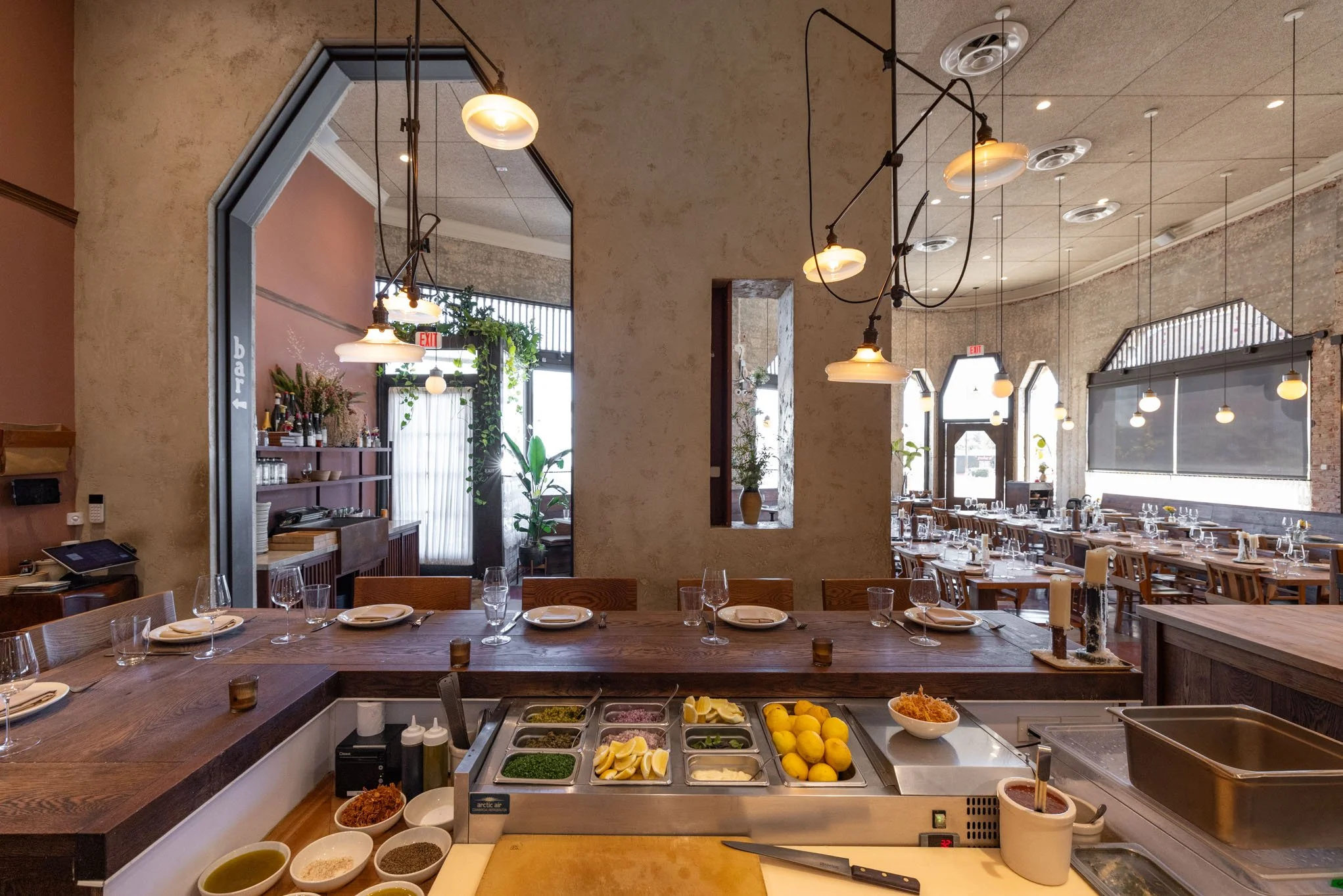 Interior of a restaurant with a dining area and a prep station with lemons, herbs, and condiments.