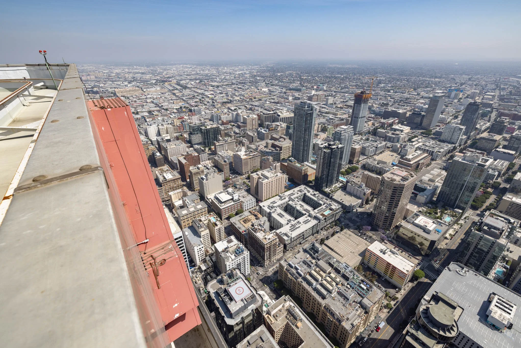 View from a skyscraper balcony overlooking a city with numerous high-rise buildings and streets.