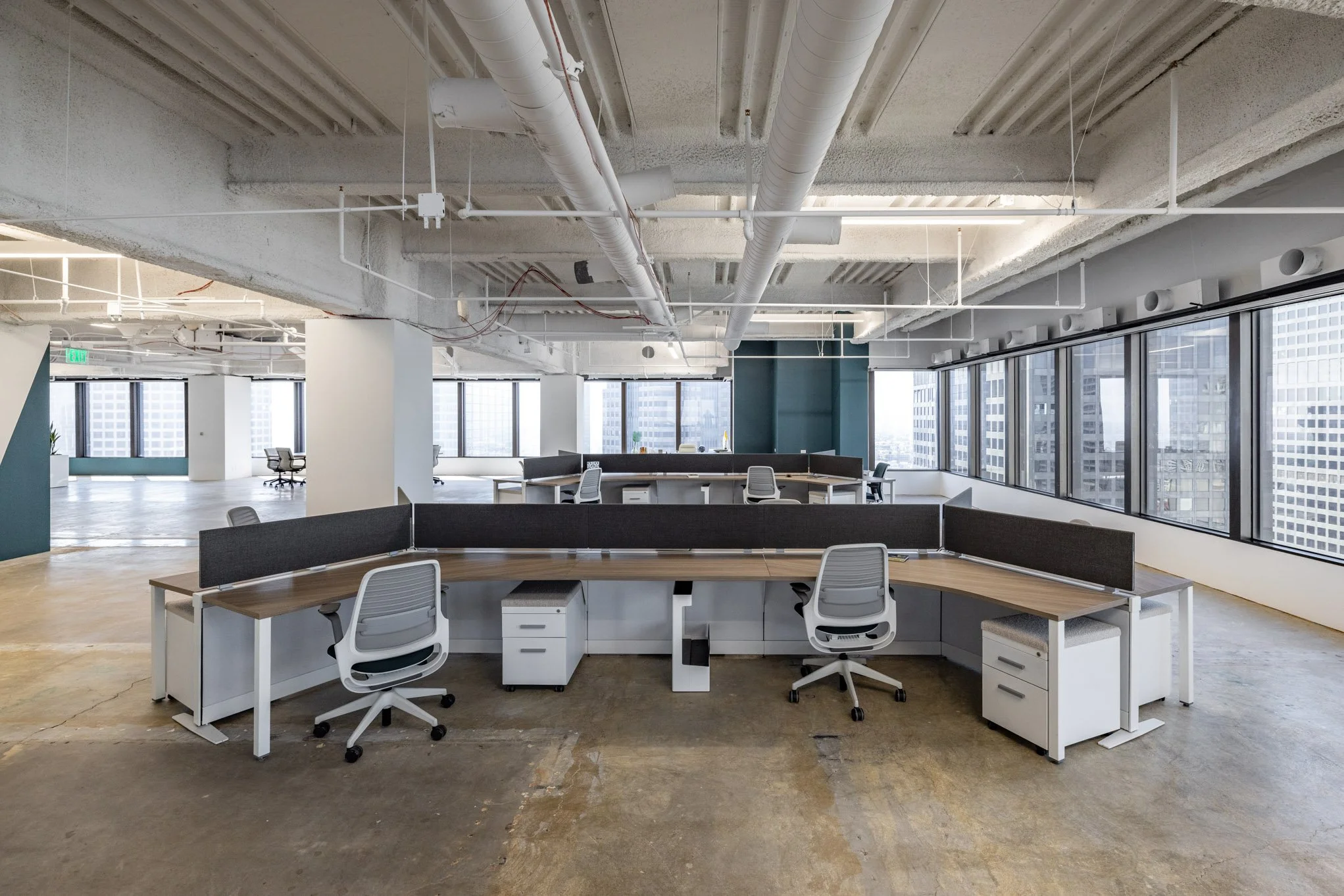 Empty modern office with multiple workstations, white chairs, and large windows in a high-rise building.