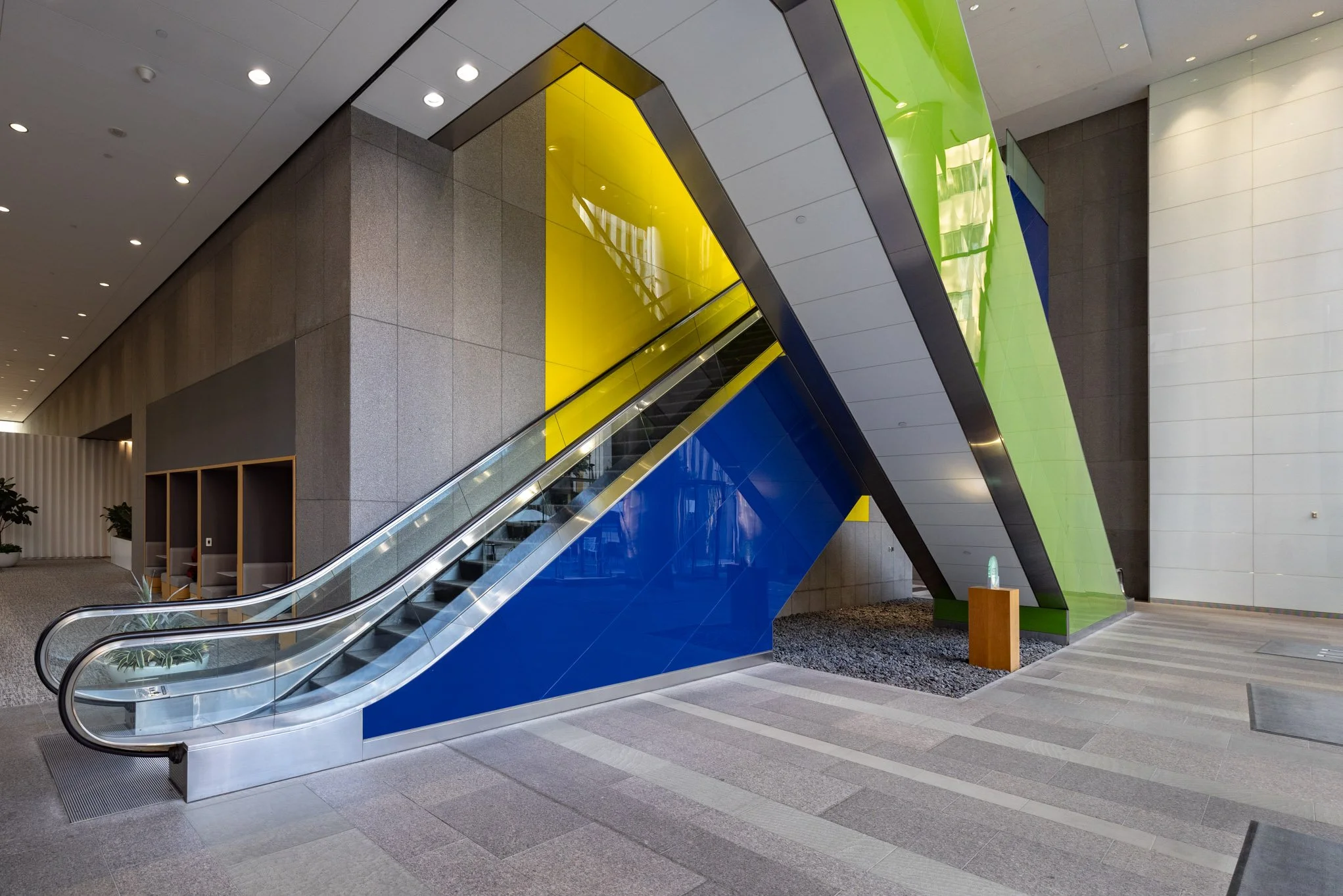 Modern indoor space with colorful escalator featuring blue, green, and black panels.