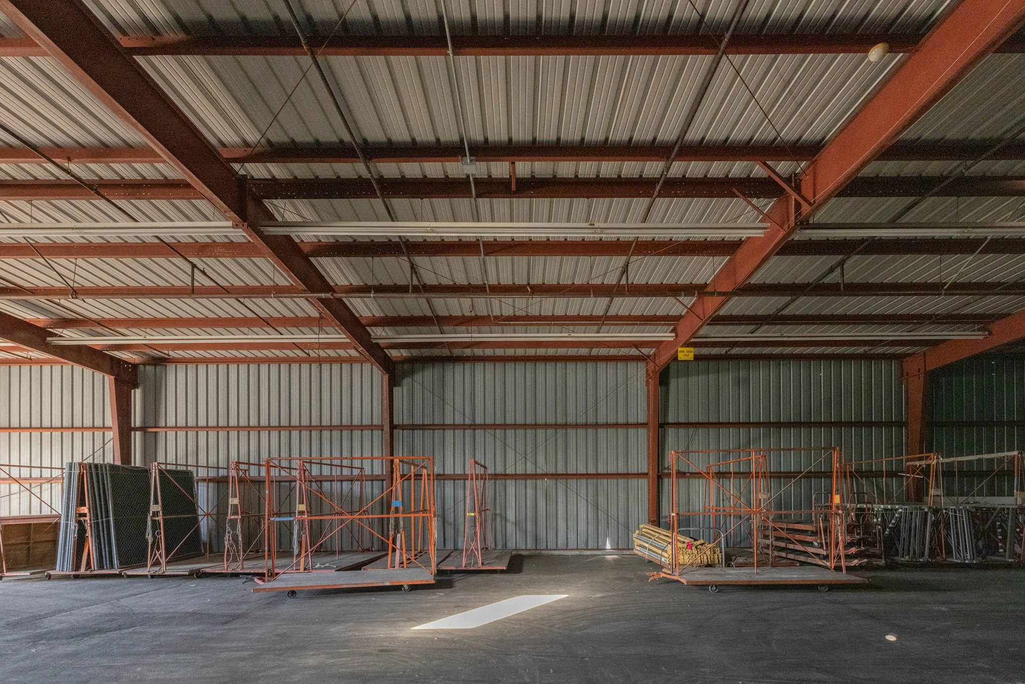 Empty industrial warehouse with storage racks and metal panels on the walls.