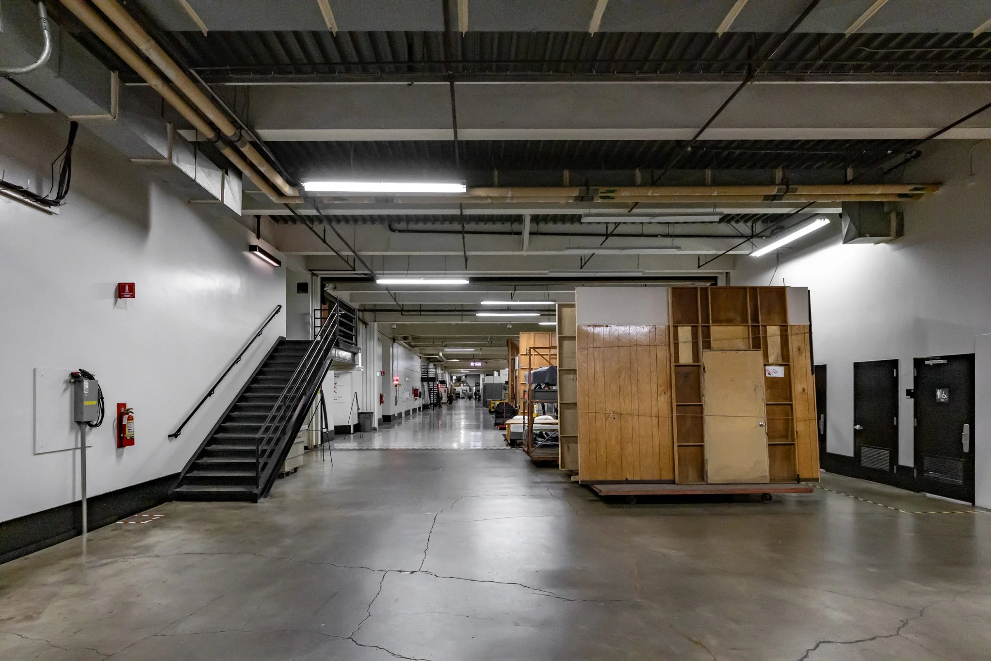 Empty industrial or warehouse space with wooden furniture and a metal staircase.