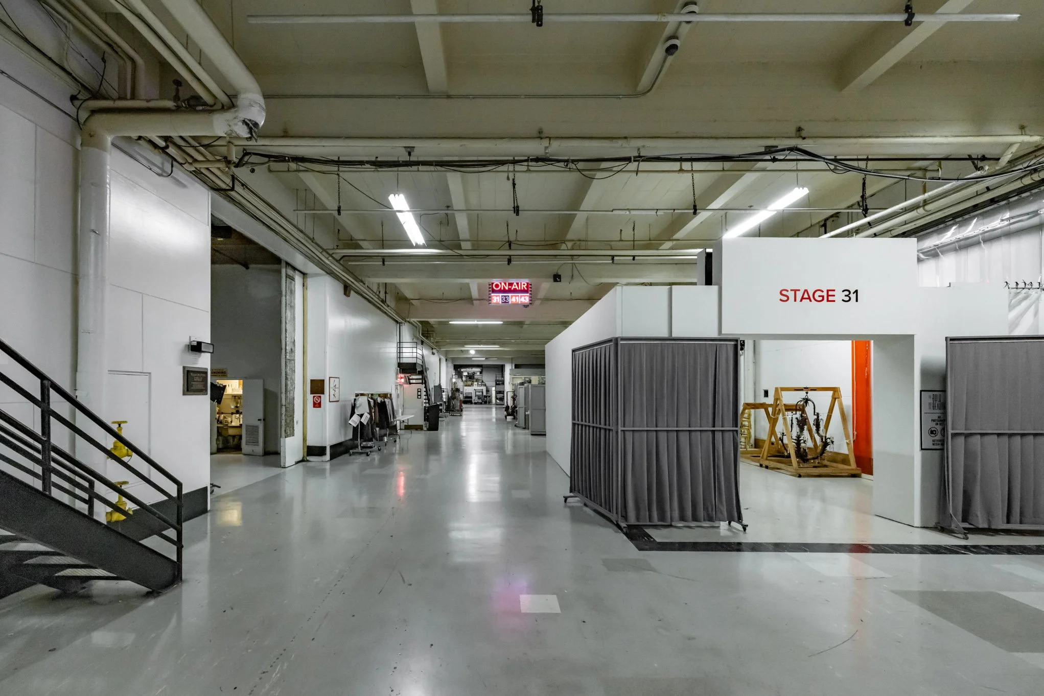 Empty backstage area in a theater or studio with a sign reading 'STAGE 31' and green curtain partitions.