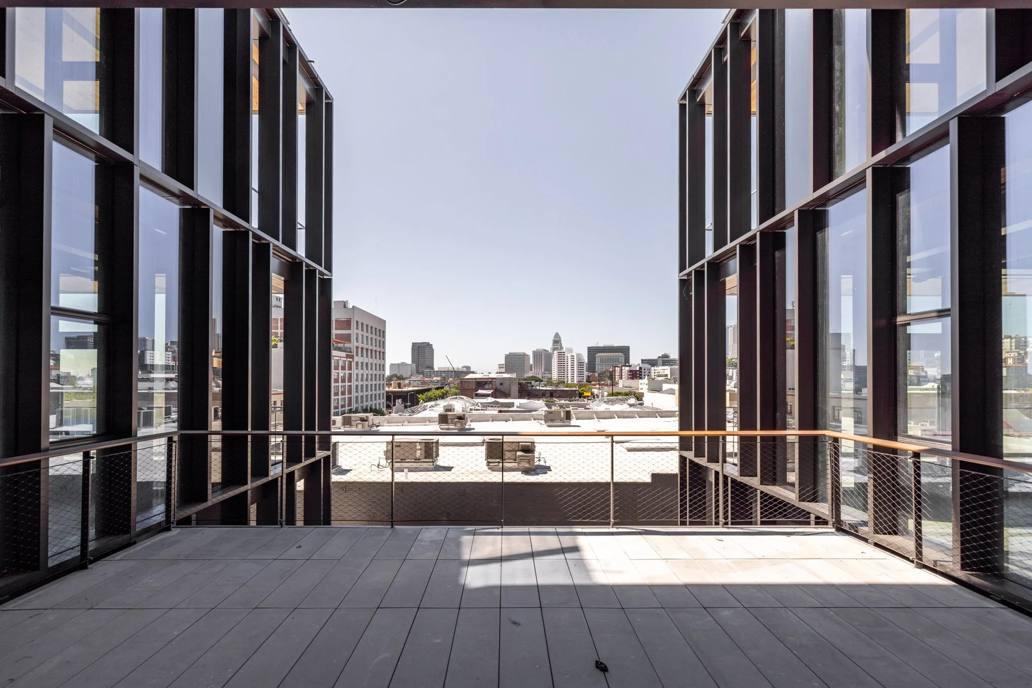 City skyline view from a modern balcony with glass walls and metal railing.