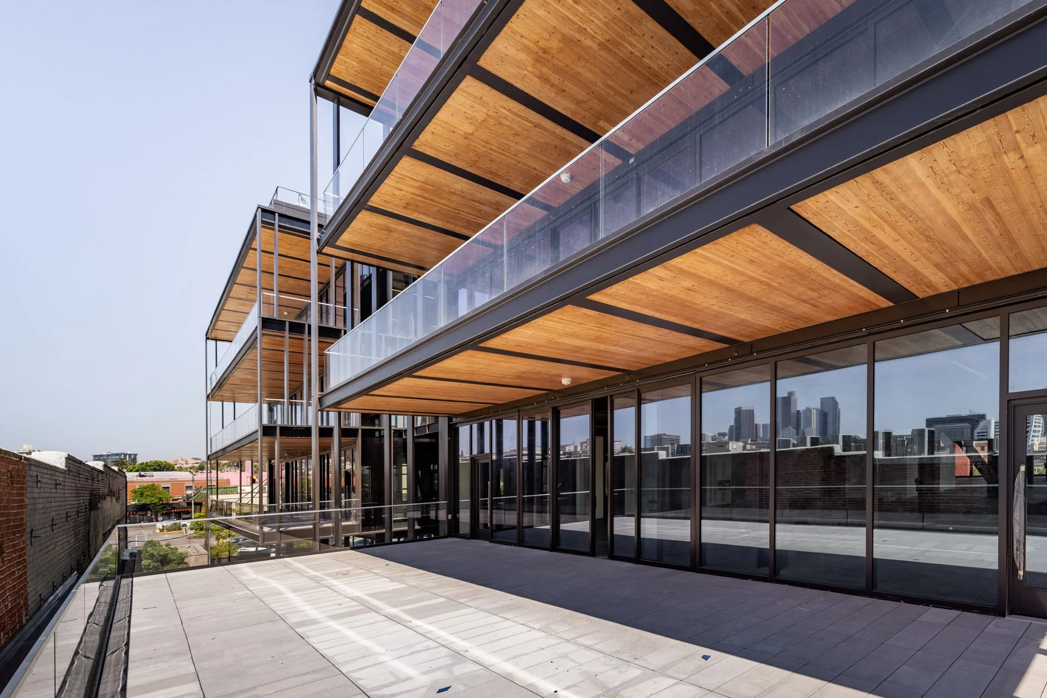 Modern building with glass doors, wooden balconies, and city skyline in background