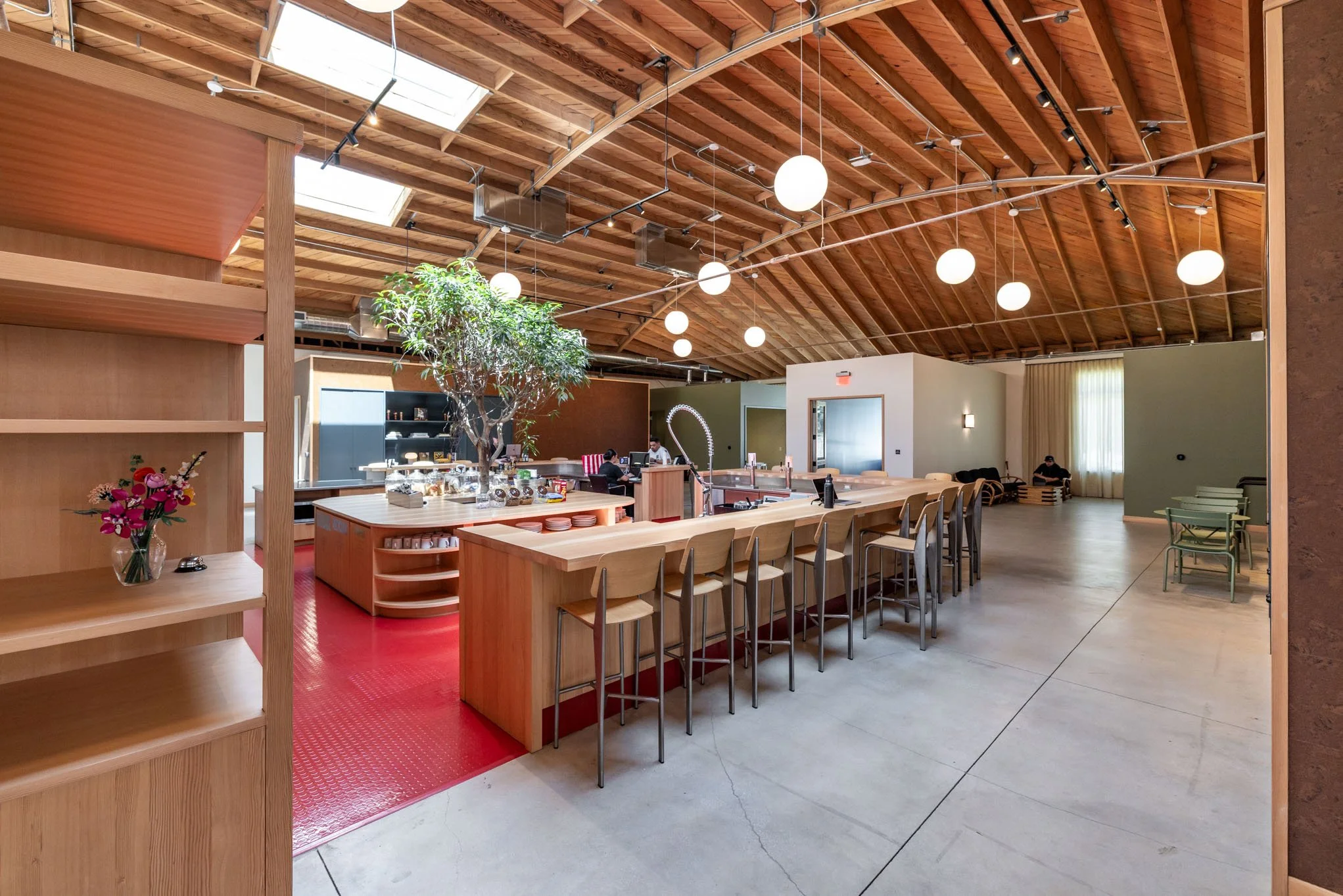 Modern indoor café with wooden ceiling, pendant lights, bar counter, and seating area.