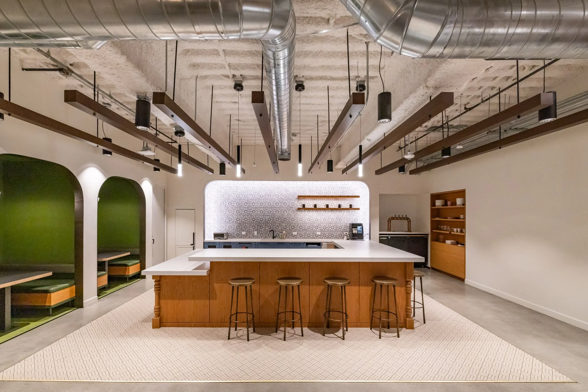 Modern kitchen with a large white island, five stools, patterned backsplash, black and wooden cabinets, open shelving, and industrial ceiling with exposed ductwork.