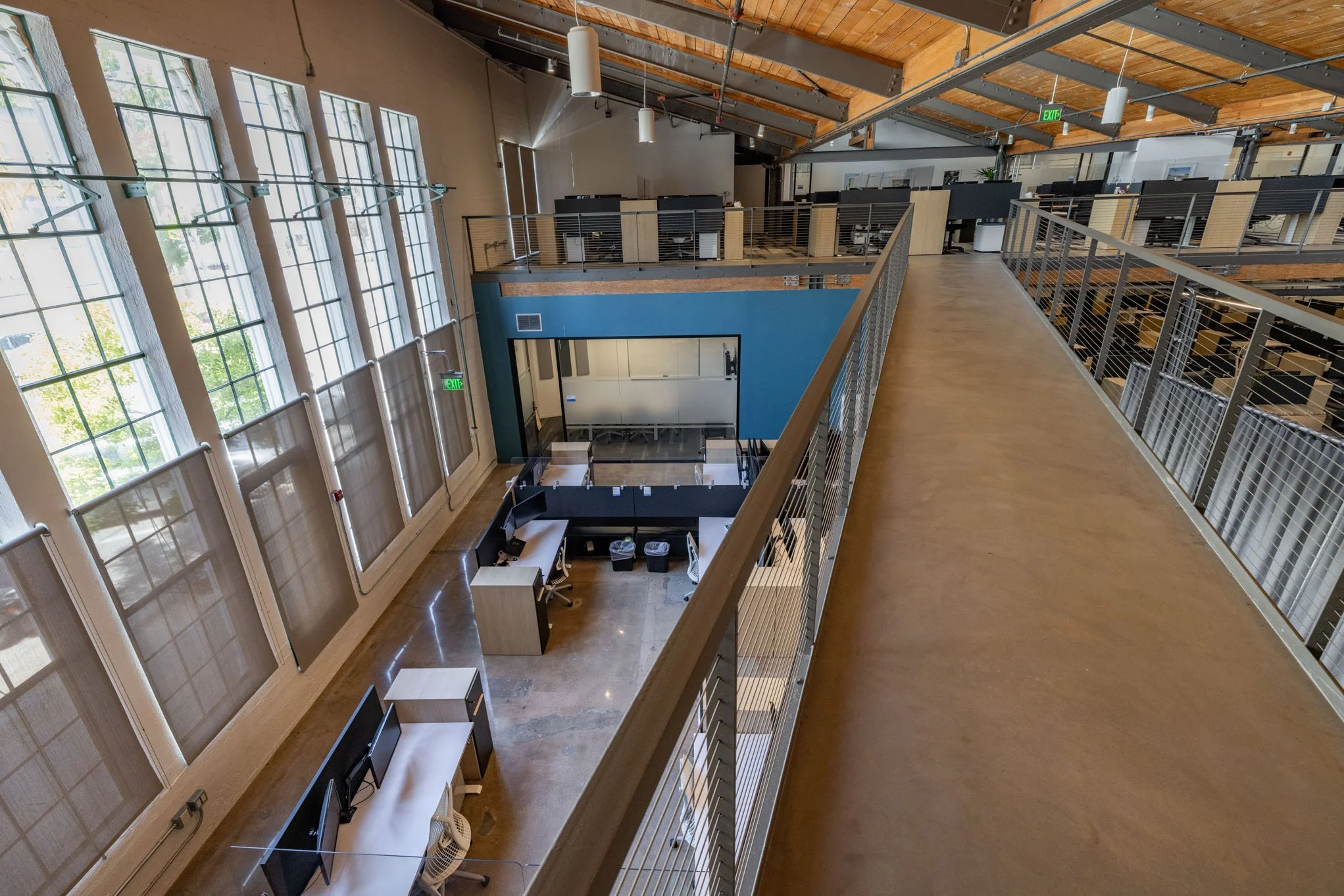 Interior view of a modern, multi-level office space with large windows, desks, and seating areas.