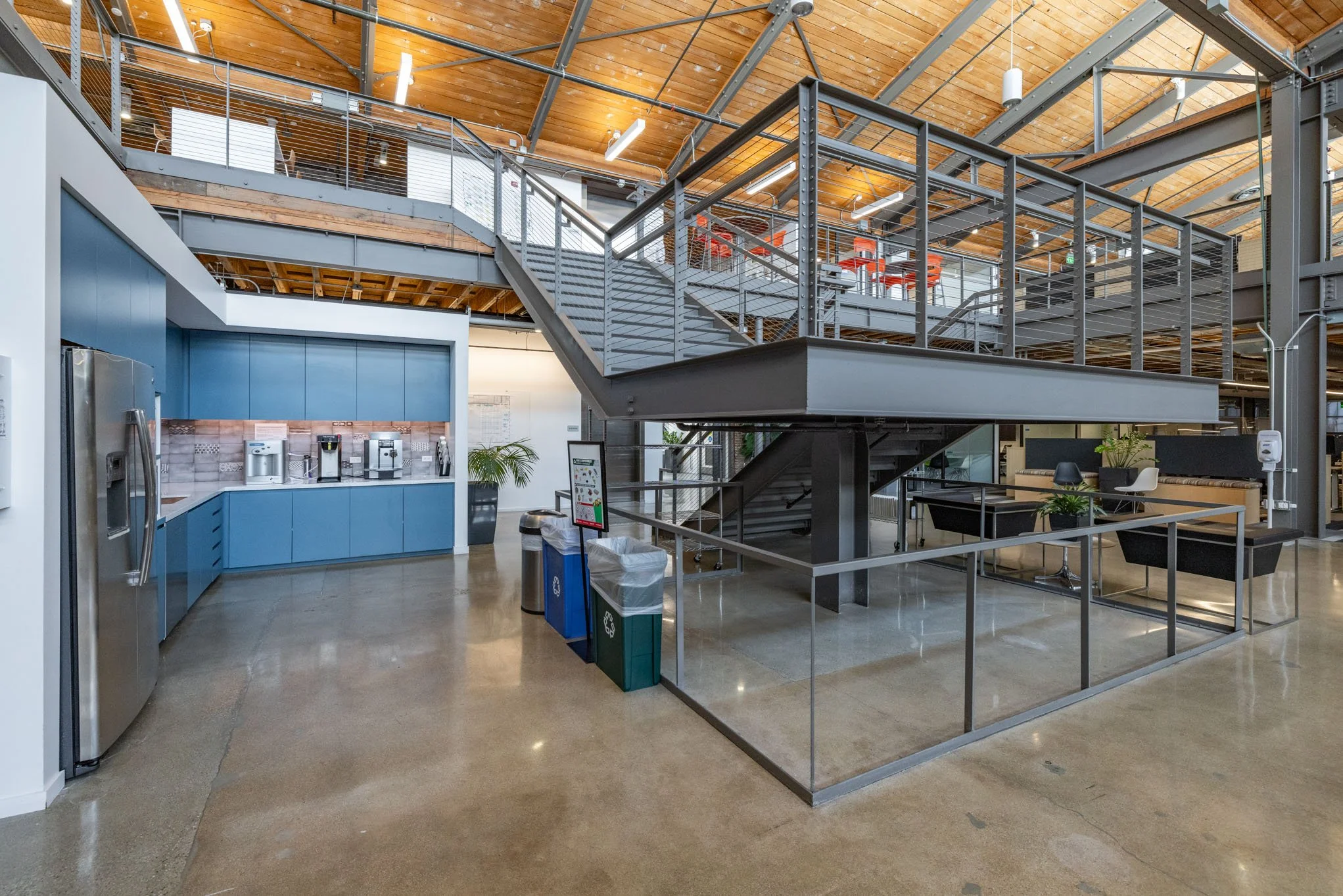Modern office common area with a staircase, coffee station, and seating area