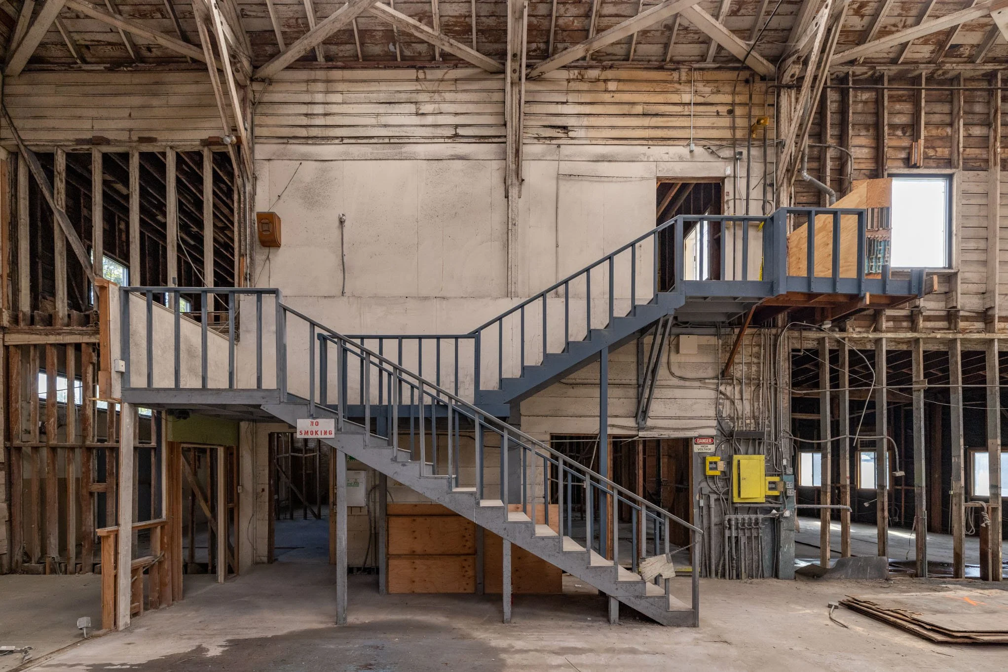 Interior of a building under construction with a gray metal staircase and exposed wooden framing.