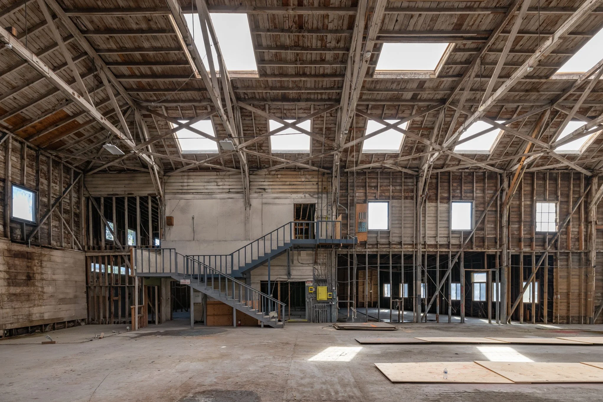 Interior of a building under construction with exposed wooden framing, skylights in the ceiling, and an unfinished stairway.